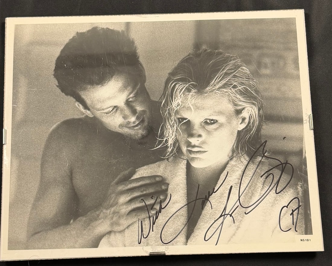 Kim Basinger and Mickey Rourke Signed 9 1/2 Weeks Publicity Photograph: A black and white publicity photograph featuring actors Mickey Rourke and Kim Basinger in a scene from the 1986 film 9 1/2 Weeks. The image depicts a close-up of the two actors, with Basinger in a whi