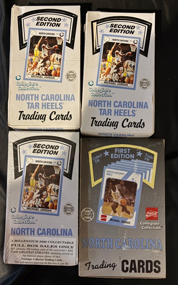 1990 Collegiate Collection North Carolina Tar Heels Trading Card Boxes: A collection of vintage collegiate basketball trading card boxes produced by Collegiate Collection, featuring the North Carolina Tar Heels. The group includes Second Edition white boxes and a First Ed