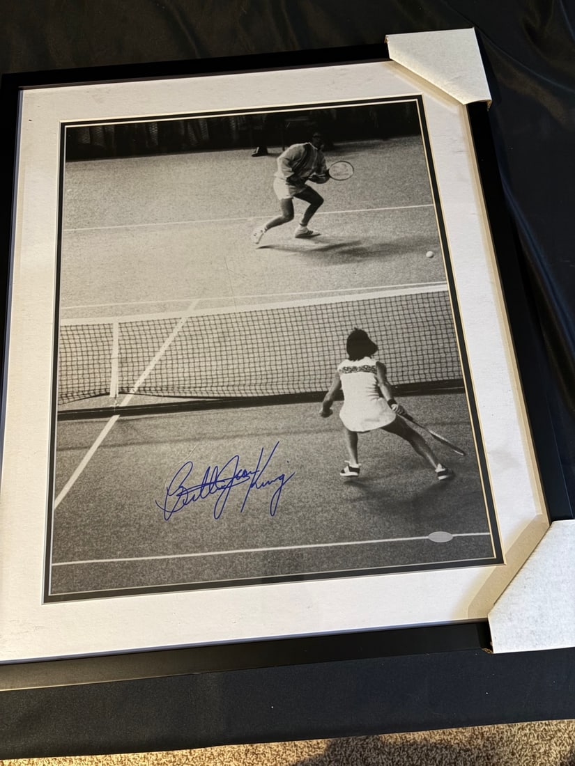 Billie Jean King Signed Battle of the Sexes 16x20 Photograph: This lot consists of a black and white photograph capturing the 1973 Battle of the Sexes tennis match between Billie Jean King and Bobby Riggs. The photograph is hand-signed by Billie Jean King in blu
