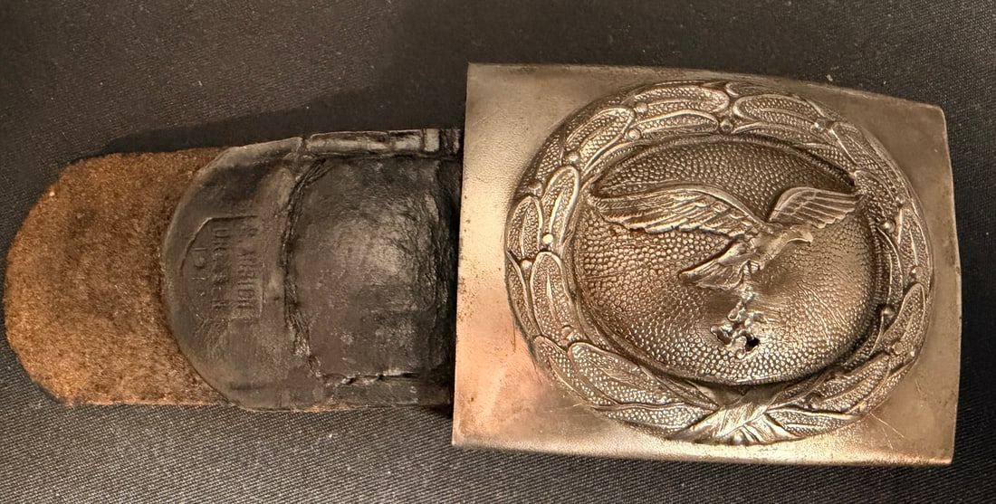 WWII Luftwaffe Belt Buckle: Manufactured by F. W. Assmann and Soehne of Ludenscheid, this Luftwaffe Enlisted Man / NCO belt buckle is of one-piece aluminum construction. The obverse features a pebbled face with a central oval wr