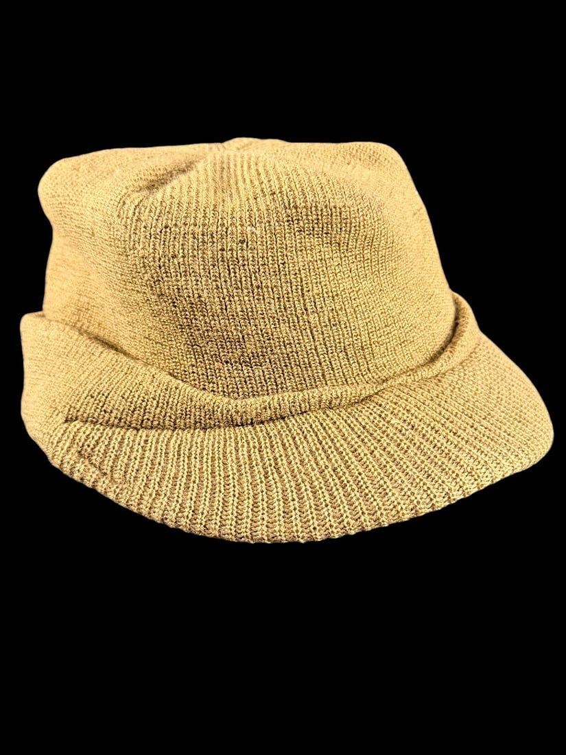 WWII Jeep Cap: A US Army M1941 pattern wool knit cap, popularly known as a Jeep Cap. This olive drab wool headgear features a characteristic short, stiffened visor and a wide, integrated fold-down cuff intended for