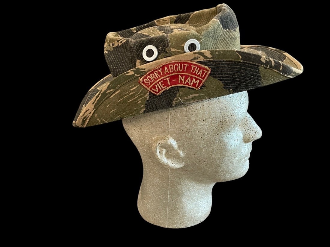 Vietnam Tiger Stripe Boonie Hat: This is a short-brimmed boonie style bush hat featuring a tigerstripe camouflage pattern, a design frequently utilized by U.S. Special Forces and South Vietnamese units during the Vietnam War. The