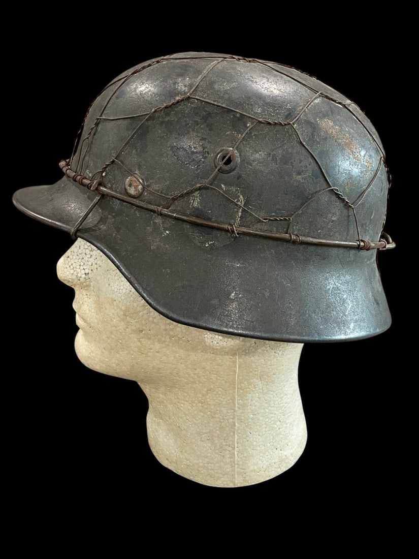 German WWII M40 SD Wire Helmet Named: This lot features a scarce and highly desirable German Model 1940 (M40) Single Decal Army (Heer) Combat Helmet enhanced with a period, field-applied wire camouflage system. The M35 model is recognized