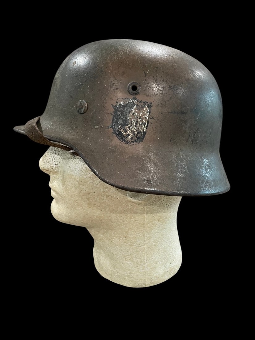 WWII German M40 Single Decal Named Camo Helmet: A WWII German M40 Heer Army combat helmet manufactured by Eisenhuettenwerke, Thale. The steel shell features the characteristic integral stamped ventilation holes and a rolled rim. The exterior is fin