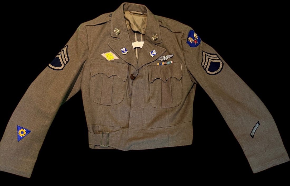 WWII EM AAF Ike Jacket with Stunning British-Made Firmin Gunner Wings: The left shoulder displays a USAAF winged star shoulder sleeve insignia. The right lower sleeve bears a triangular blue and yellow Army Air Forces Technical Training Command patch, while the right bre