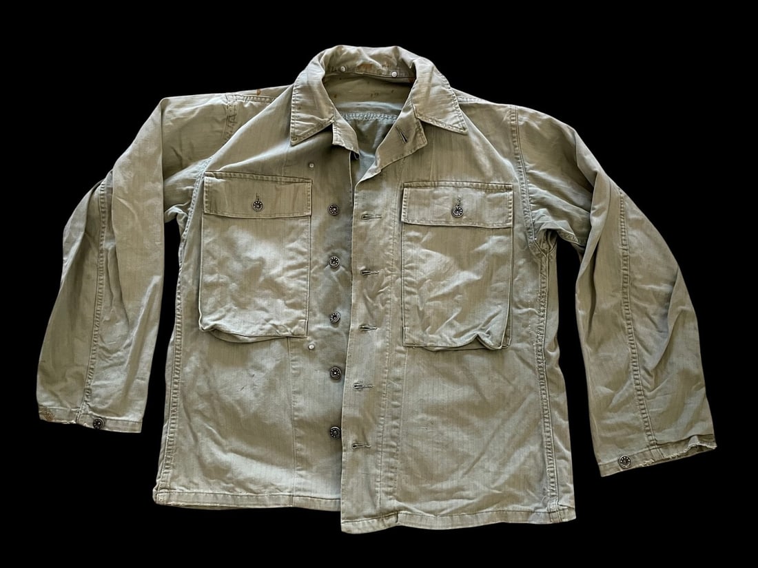 WWII US M43 Army HBT Shirt: United States military fatigue shirt, identified as the M1943 or second pattern Herringbone Twill HBT utility jacket. The garment is constructed from olive drab cotton in a herringbone weave. It featu