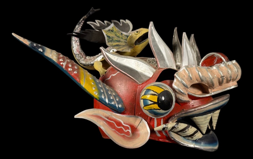 Dragon Mask: Brightly painted dragon or mythical creature mask featuring large eyes, carved teeth, horns, and elaborate painted details.