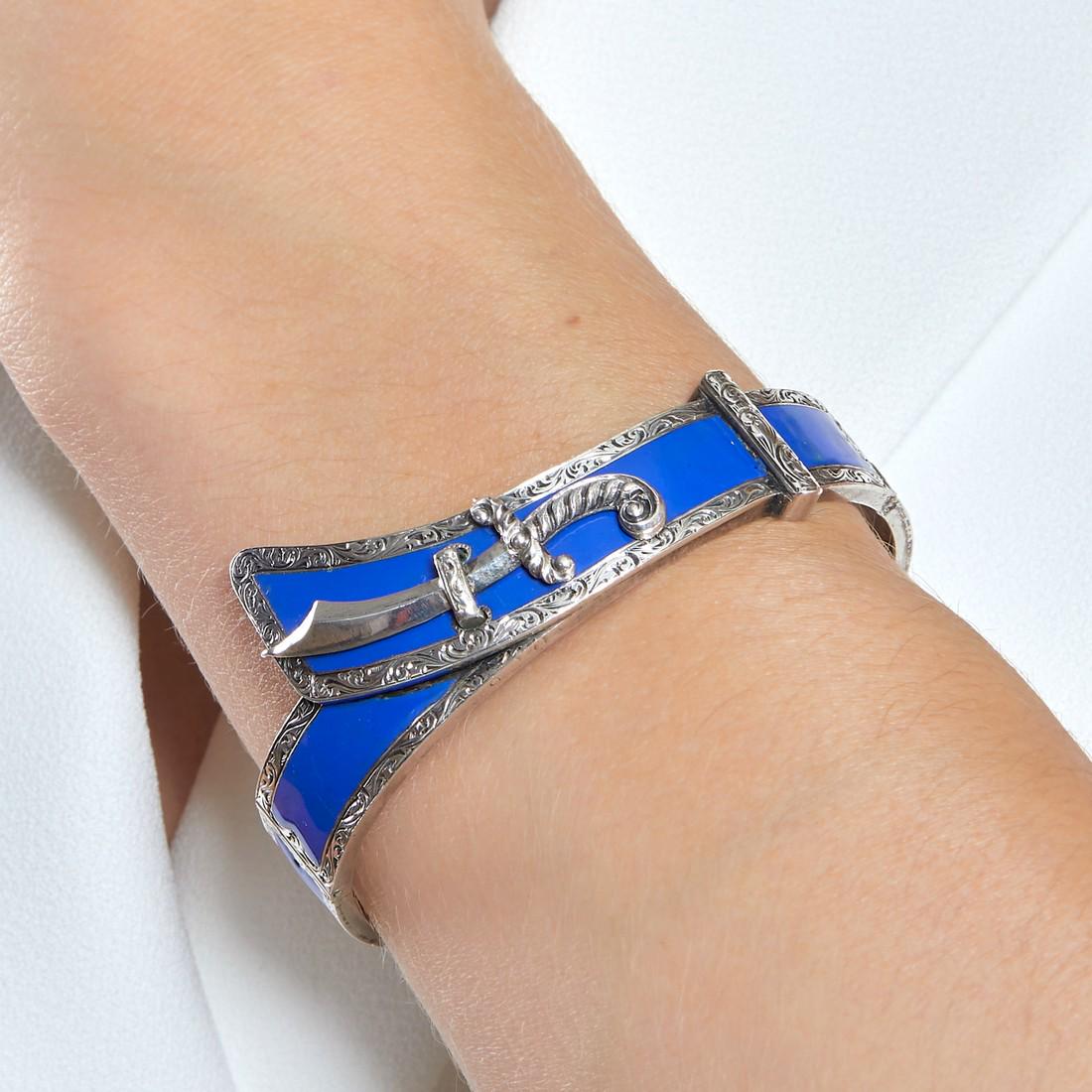 TRAVAIL FRANÇAIS ANNÉES 1840 BRACELET: TRAVAIL FRANÇAIS ANNÉES 1840 BRACELET CEINTURE ÉMAIL Le bracelet rigide ouvrant en argent émaillé bleu et ciselé. Il porte en applique un sabre. Poids brut : 38,98 gr. To