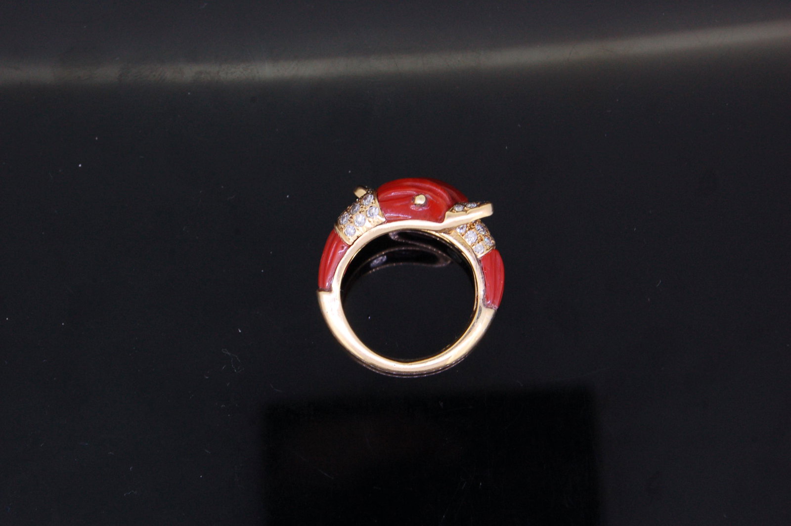 CORAL AND DIAMOND TWIN DOLPHIN CROSS RING: CORAL AND DIAMOND TWIN DOLPHIN CROSS RING, designed as two dolphin heads set with rigde cut coral and diamonds. Size K. 7 grams.