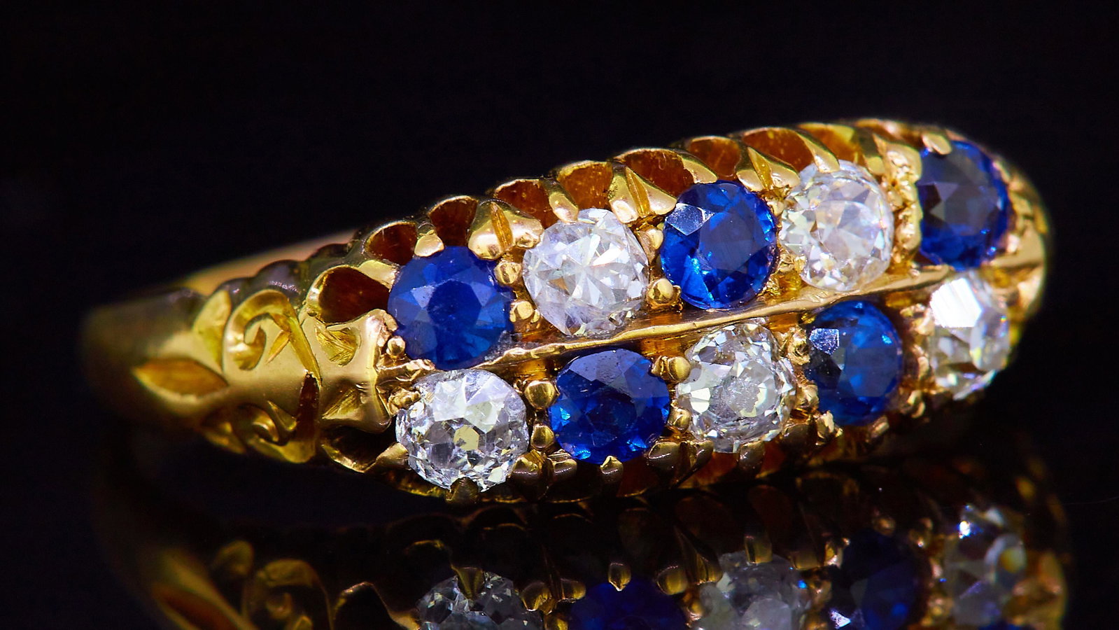2-ROW SAPPHIRE AND DIAMOND RING: 2-ROW SAPPHIRE AND DIAMOND RING, in precious yellow metal. Alternatedly set with blue sapphire and ddiamond, in 2 rows. The shoulders with scrolling relief design. Size M. 4 grams.
