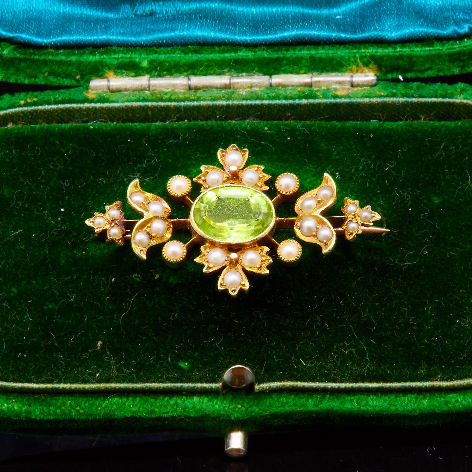 NO RESERVE, ANTIQUE PERIDOT AND PEARL BROOCH: NO RESERVE, ANTIQUE PERIOT AND PEARL BROOCH, set with a central oval peridot of approx. 1.70 ct. Flanked with pearls. L. 3.3 cm. 4.2 grams. With a box.