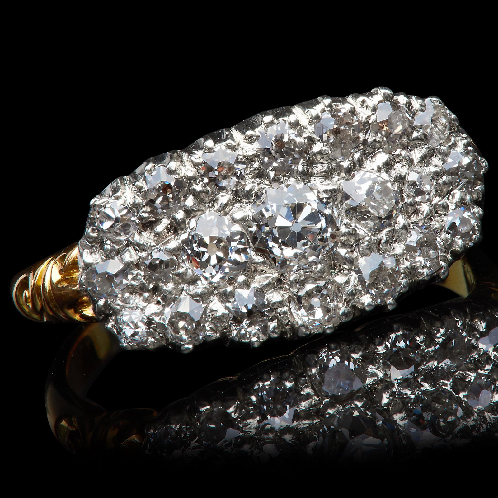 ANTIQUE DIAMOND CLUSTER RING: ANTIQUE DIAMOND CLUSTER RING, in 18 ct. gold. Set with larger diamonds to the center, flanked with smalled diamonds to the sides. Diamonds totalling approx. 1.20 ct. Size P. 4.9 grams.