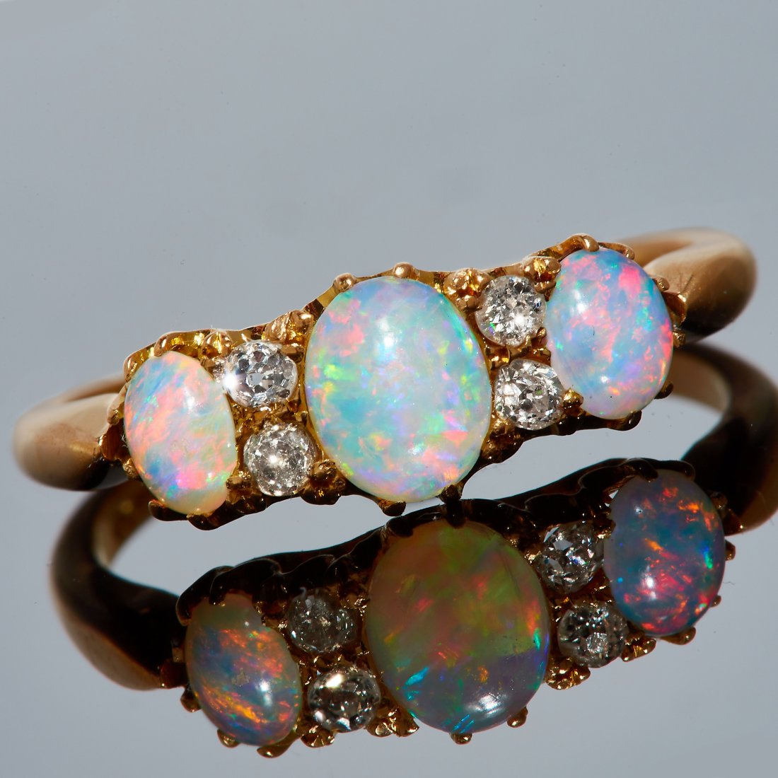 OPAL AND DIAMOND RING: OPAL AND DIAMOND RING, in 18 ct. gold. Set with 3 cabochon cut opals, flanked with diamonds. Size N 1/2. 2.8 grams.