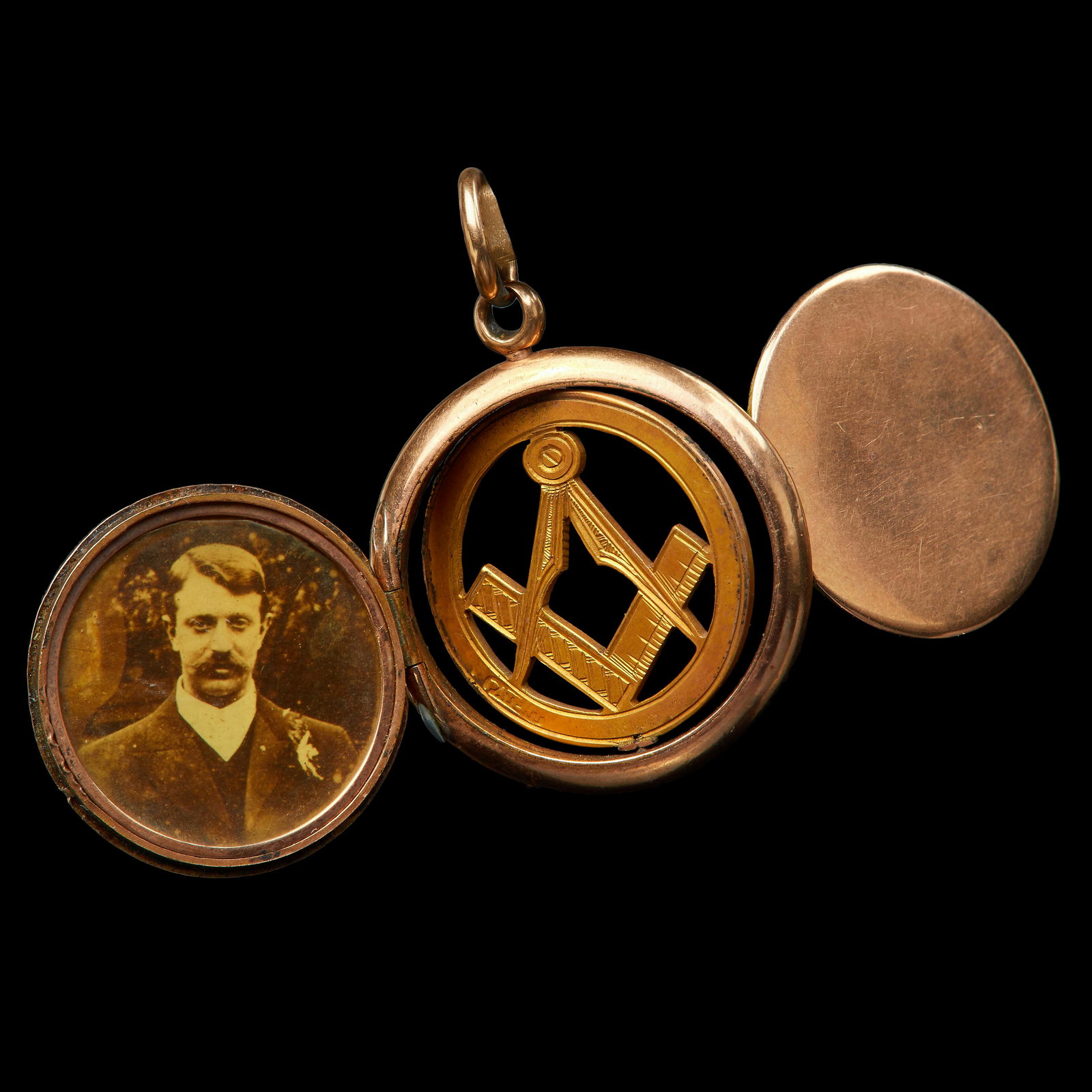 MASONIC HIDDEN DOUBLE LOCKET PENDANT: MASONIC HIDDEN DOUBLE LOCKET PENDANT, the locket with 2 hinges, one with apicture of a man, the other with a picture of a woman. The centre of swivel design, with a hidden Compass and square. Diam. 2.