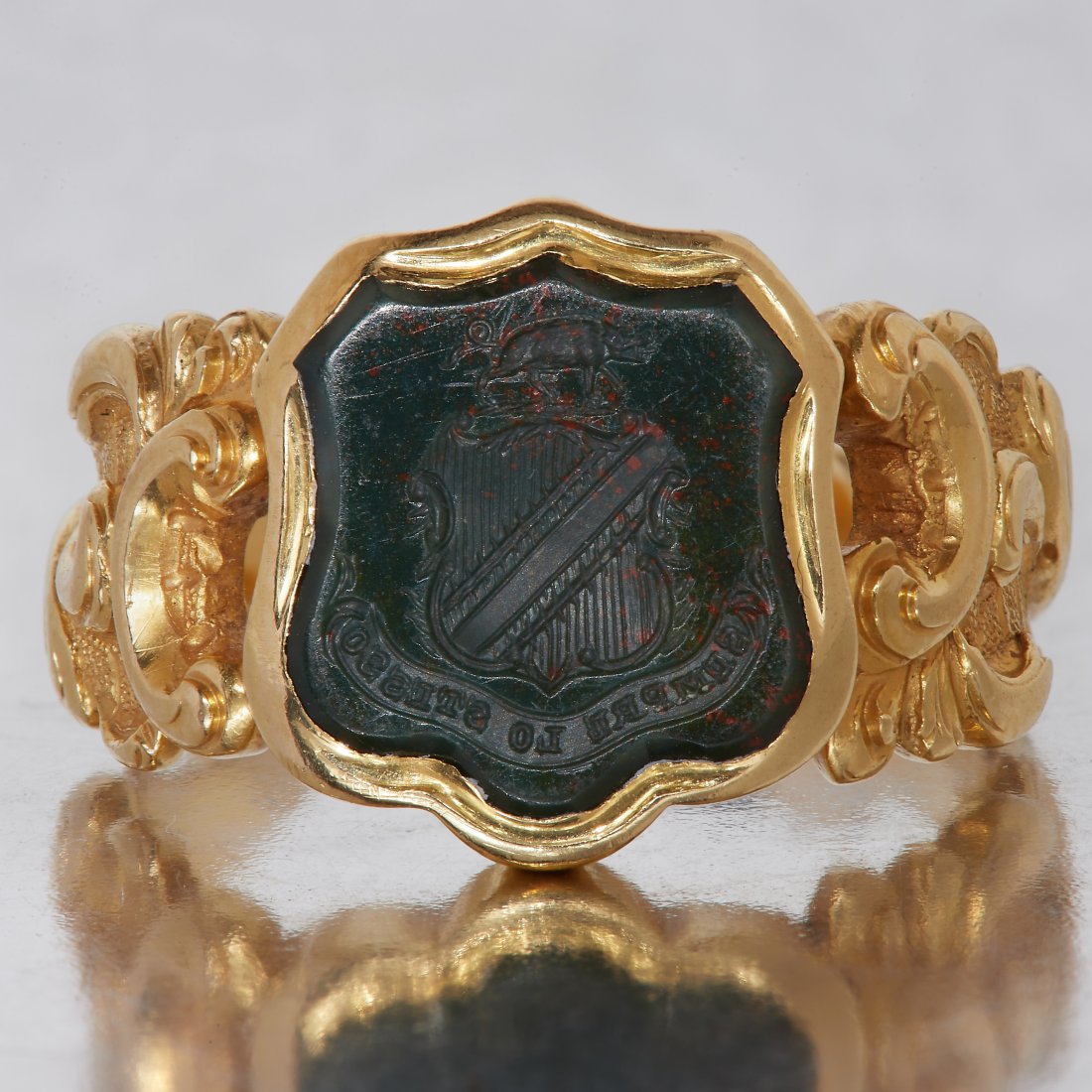 ANTIQUE INTAGLIO CARVED BLOODSTONE SEAL RING: ANTIQUE INTAGLIO CARVED BLOODSTONE SEAL RING, The carved intaglio seal in the shape of a shield, depicting a board above a shield and ribbon of text underneath: Sempre Lo Stesso. size L. 8.1 grams.