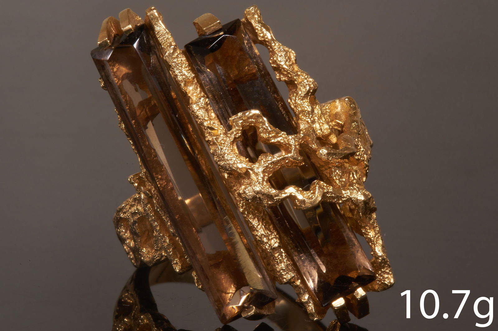 RETRO SMOKY QUARTZ RING: RETRO SMOKY QUARTZ RING,High carat gold.2 elongated smoky quartz.Abstract design.Size R 1/210.7 grams.In the manner or Andrew Grima.