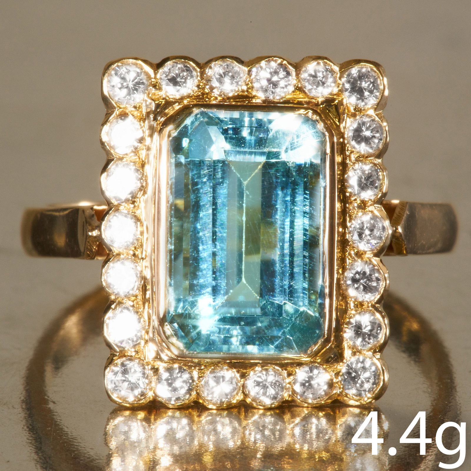 AQUAMARINE AND DIAMOND CLUSTER RING: AQUAMARINE AND DIAMOND CLUSTER RING,18 ct. gold.Vibrant and rich aquamarine.Diamonds bright and lively, totalling approx. 0.50 ct.Size O.4.4 grams.