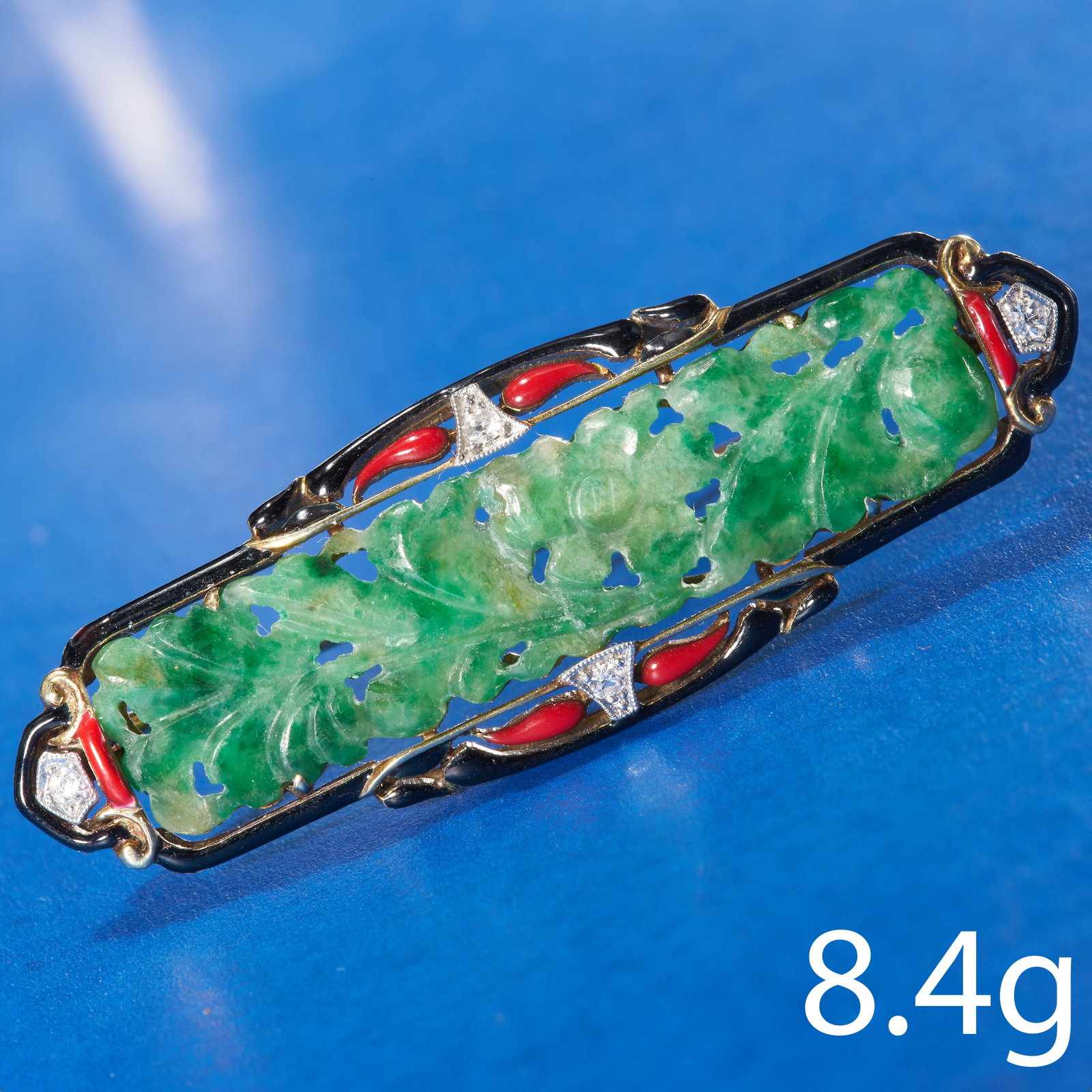 ART-DECO JADE, ENAMEL AND DIAMOND BROOCH: ART-DECO JADE, ENAMEL AND DIAMOND BROOCH,High carat gold.Carved green jade center plaque.The surmount with black and red enamel, in good condition.Accentuated with diamonds.W. 5.2 cm.8.4 grams.