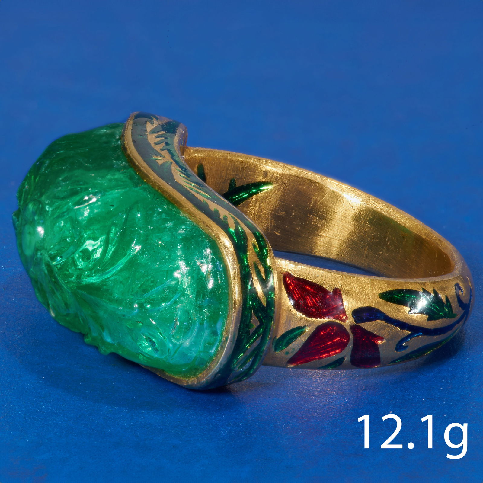 MOGHUL EMERALD AND ENAMEL RING: MOGHUL EMERALD AND ENAMEL RINGin high carat gold.Emerald of approx. 10.92 ct. Accentuated with red blue and green enamel, in great condition.Size L 1/2.12.1 grams.Fine carved emerald, lovely enamel ac