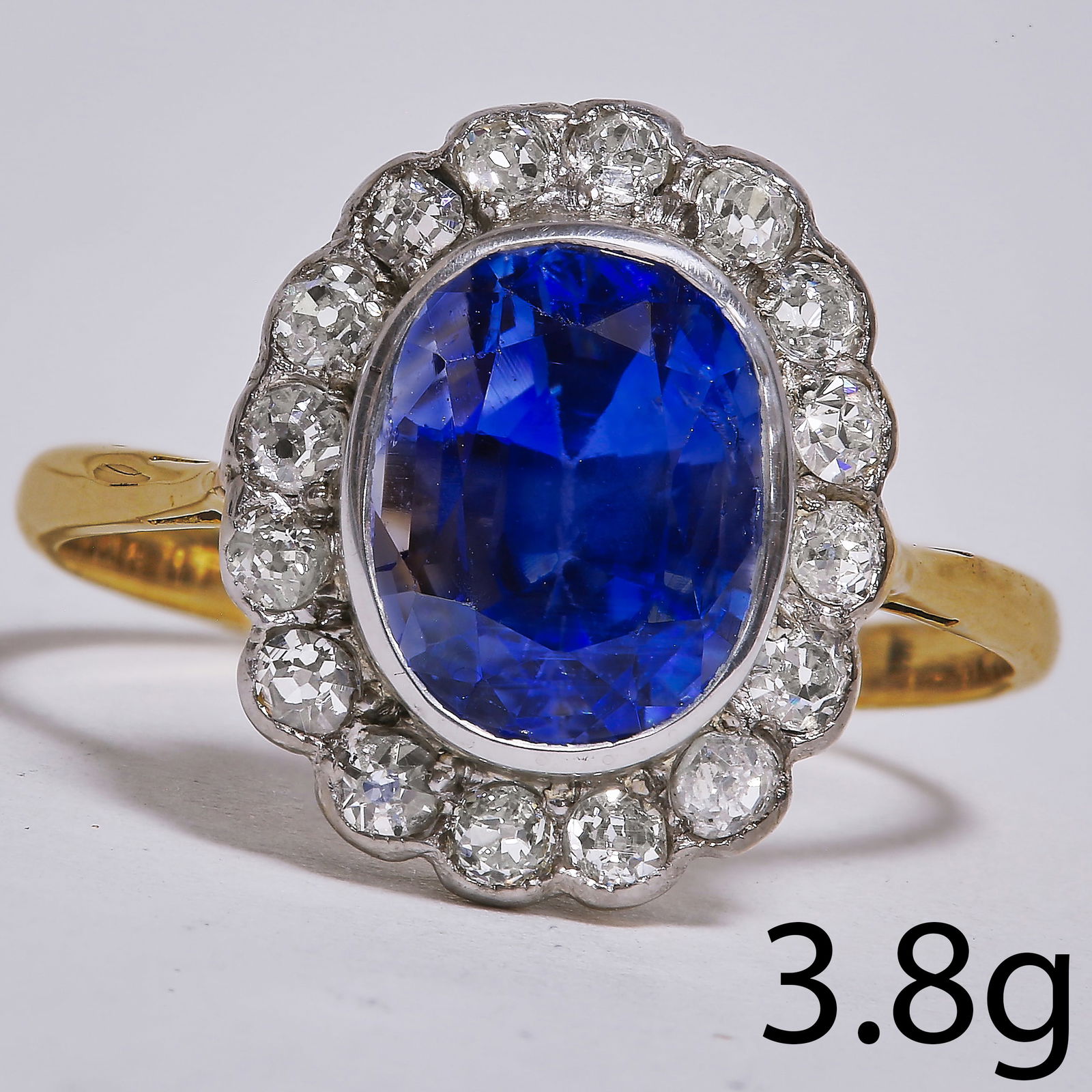 SAPPHIRE AND DIAMOND CLUSTER RING: SAPPHIRE AND DIAMOND CLUSTER RING,3.8 grams, 18 ct. gold.Vibrant sapphire of approx. 3.77 ct.Diamonds bright and lively.Size O 1/2.