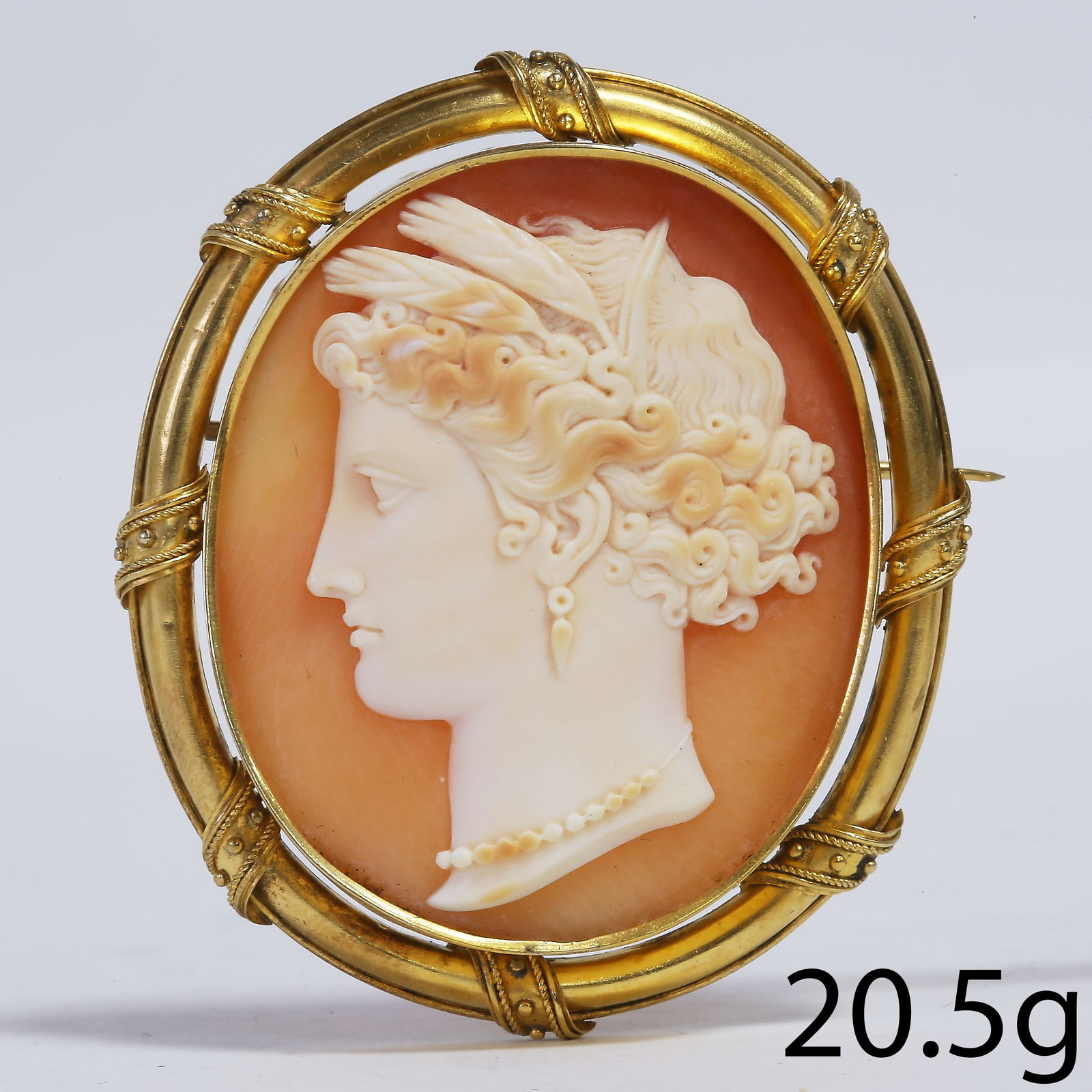 CARVED SHELL CAMEO BROOCH: CARVED SHELL CAMEO BROOCH,20.5 grams, testing high carat gold.The cameo a bust in profile of a classical woman.L. 5.6 cm.
