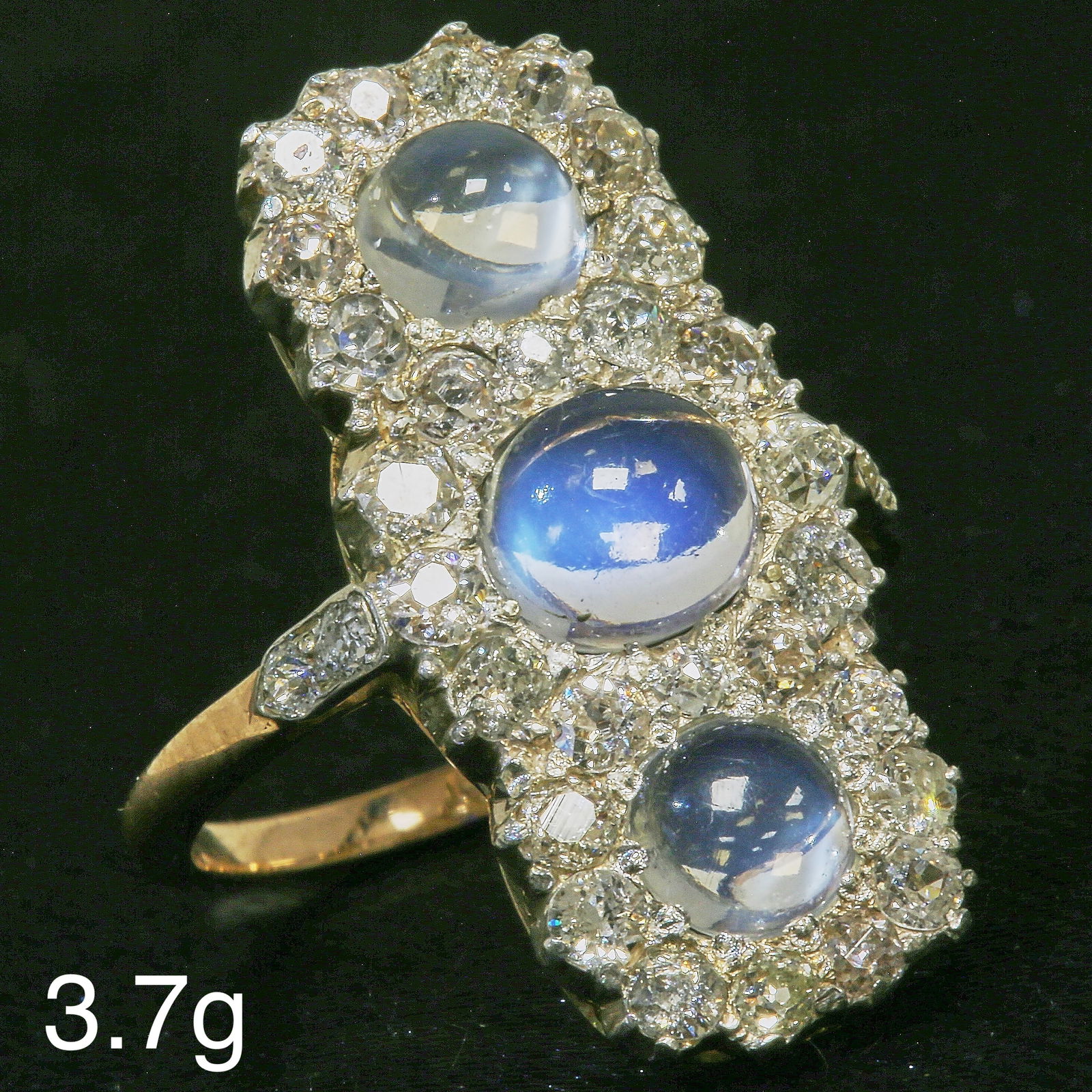 MOONSTONE AND DIAMOND TRIPLE CLUSTER RING: MOONSTONE AND DIAMOND TRIPLE CLUSTER RING,3,7 grams, testing high carat gold.Diamonds bright and lively totalling approx. 1 ct.Right and vibrant moonstones with nice blue shiller.L. head 2.6 cm.Size M