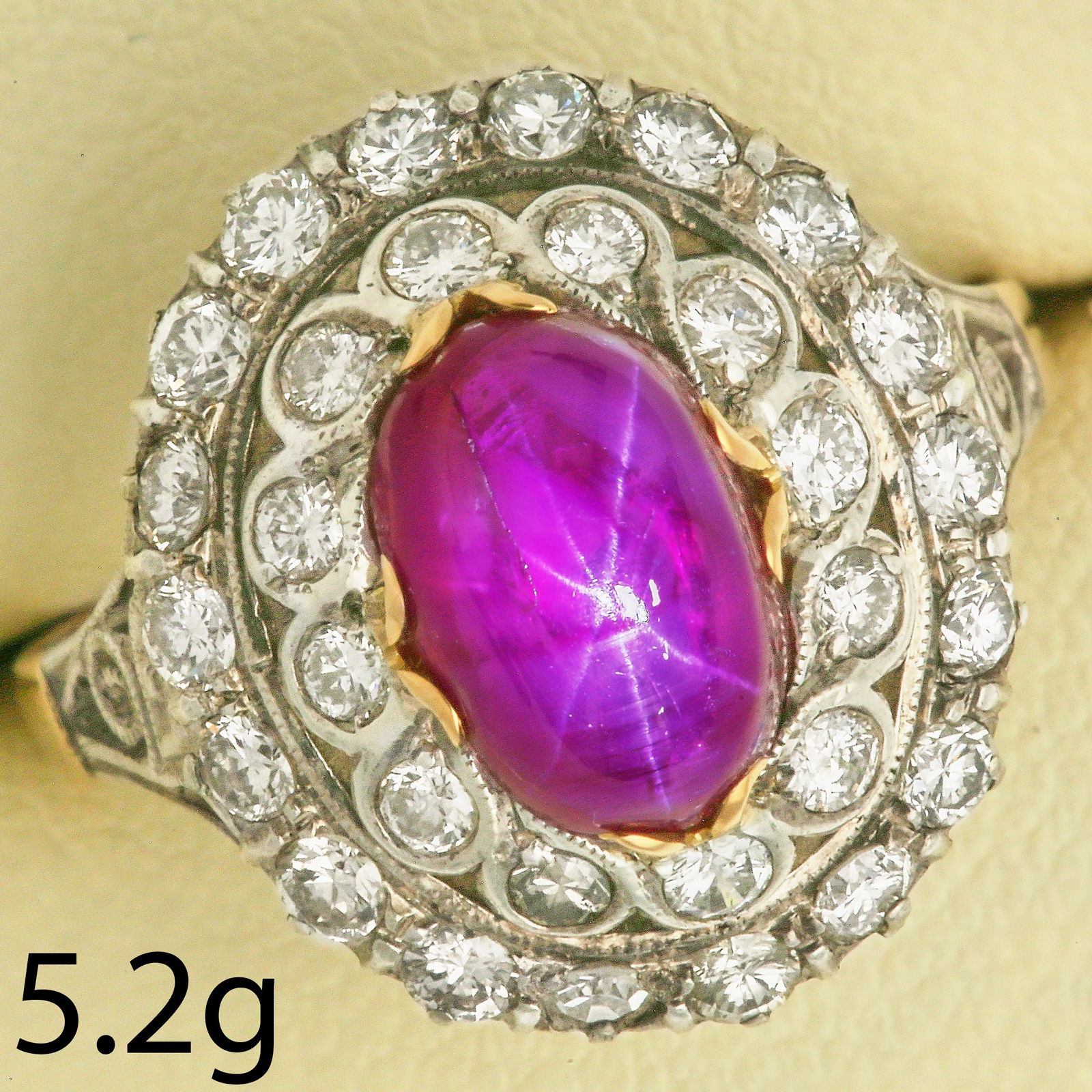 RUBY AND DIAMOND CLUSTER RING: RUBY AND DIAMOND CLUSTER RING,5,2 grams, 14 ct. gold and silver.Vibrant cabochon cut ruby of approx. 4 ct.Diamonds bright and lively.Size N.