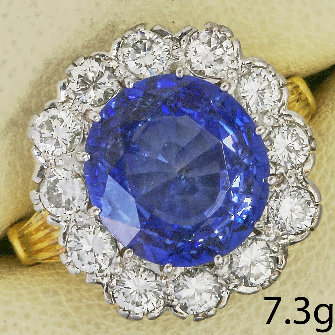FINE SAPPHIRE AND DIAMOND CLUSTER RING: FINE SAPPHIRE AND DIAMOND CLUSTER RING,7,3 grams, testing high carat gold.Rich and vibrant sapphire, of approx. 6.23 ct.Diamonds bright and lively, totalling approx. 1.20 ct.Size O.
