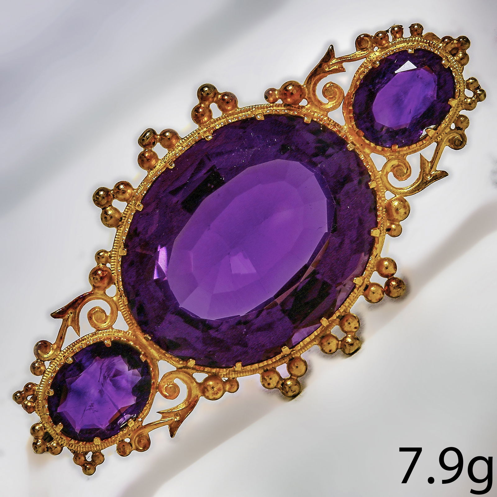 ANTIQUE AMETHYST BROOCH: ANTIQUE AMETHYST BROOCH,7.9 grams, testing high carat gold.Vibrant amethyst.Largest of approx. 20.4 mm.L. 4.4 cm.