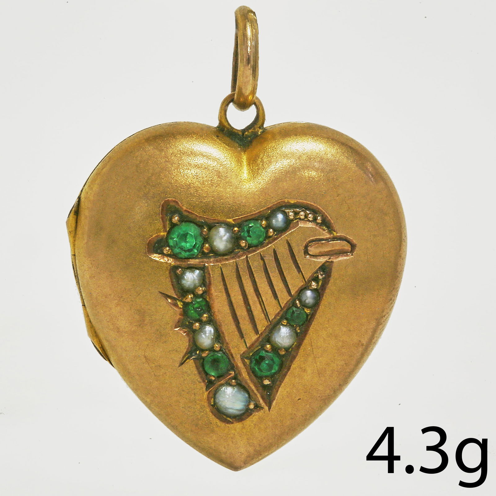 GOLD GREEN STONE AND SPLIT PEARL CELTIC (IRISH) HARP LOCKET PENDANT: GOLD GREEN STONE AND SPLIT PEARL CELTIC (IRISH) HARP LOCKET PENDANT4.3 grams.Depicting a harp within a heart shaped locket. L approx. 2.7 cm.
