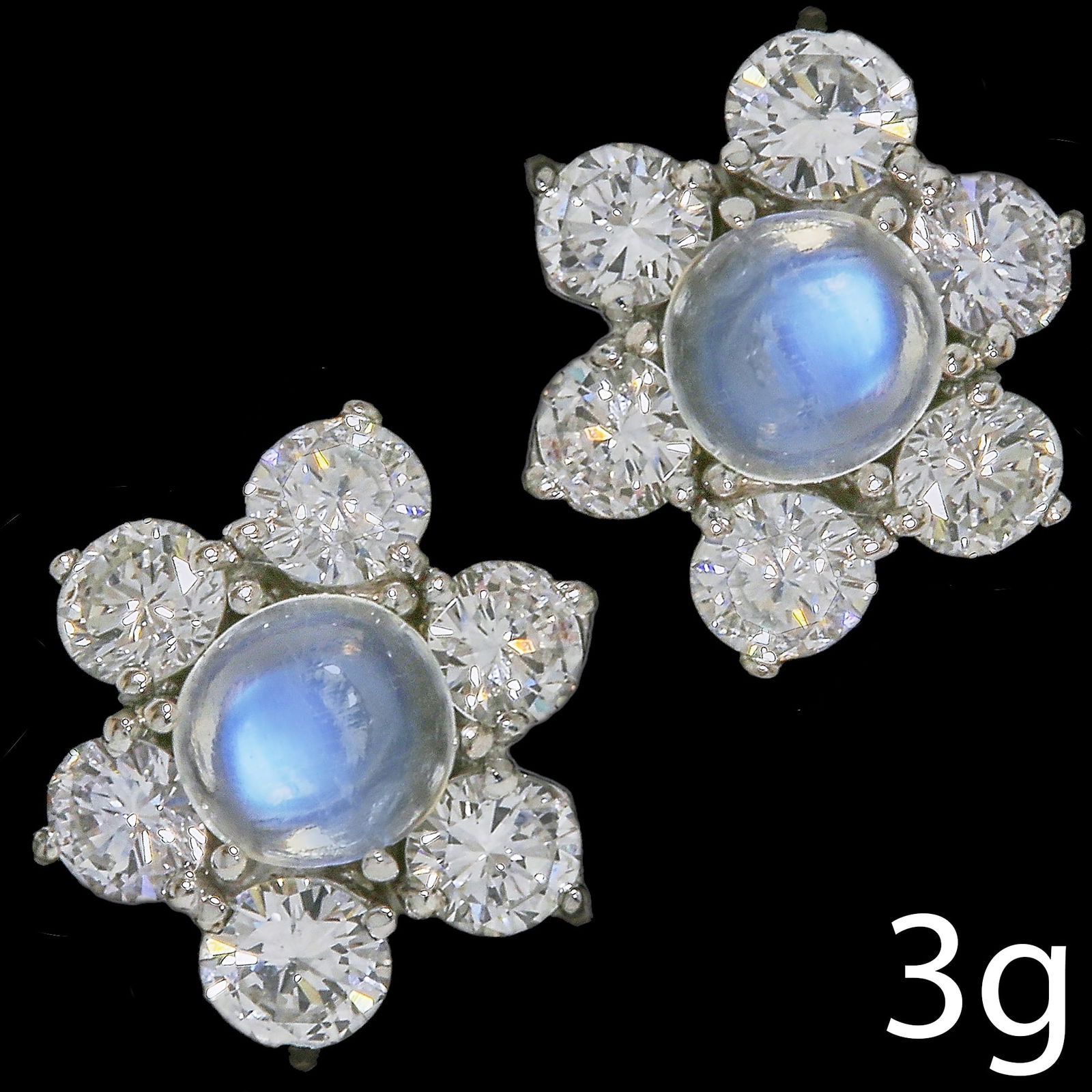 PAIR OF MOONSTONE AND DIAMOND CLUSTER EARRINGS: PAIR OF MOONSTONE AND DIAMOND CLUSTER EARRINGS,3 grams, testing high carat gold.Diamonds totalling approx. 1.20 ct.Lovely moonstones with nice blue shiller.Diam. 1.2 cm.
