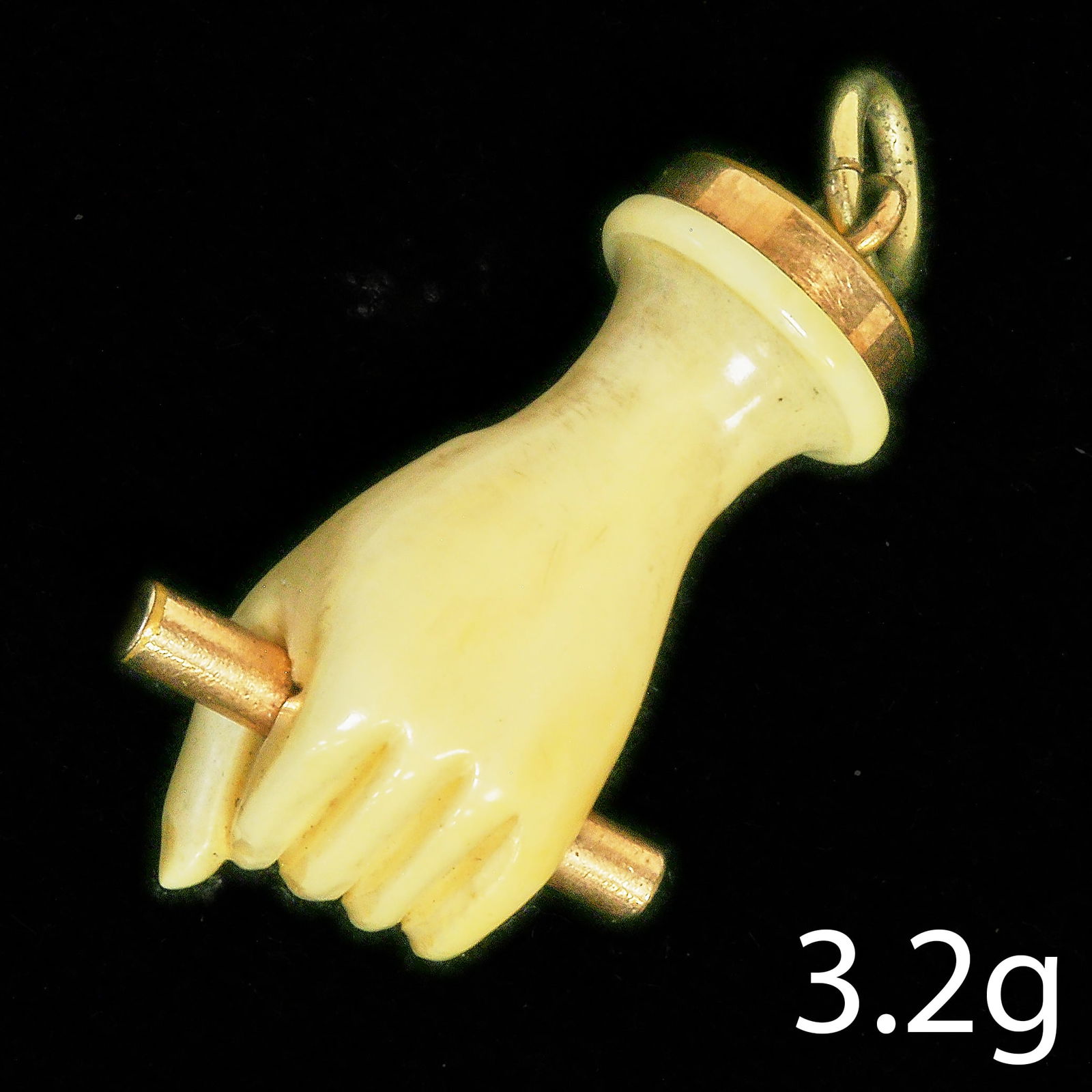 ANTIQUE BONE AND GOLD HAND CHARM PENDANT: ANTIQUE BONE AND GOLD HAND CHARM PENDANT,depicting a hand holding a stick.L. 3,5 cm.