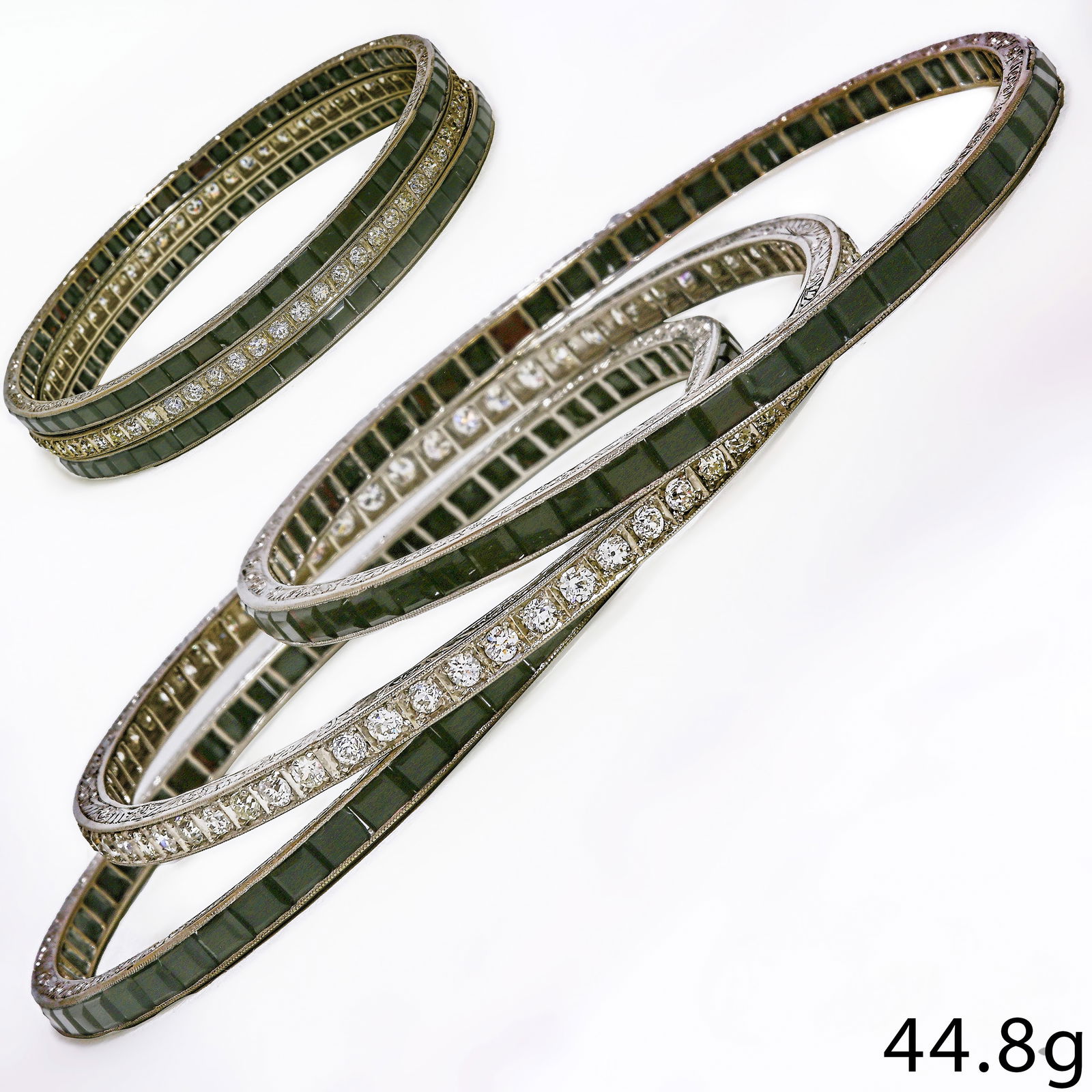 EXQUISITE SET OF 3 ART-DECO ONYX AND DIAMOND BANGLES: EXQUISITE SET OF 3 ART-DECO ONYX AND DIAMOND BANGLES,50 grams, platinum.2 bangles fully set with onyx1 bangle fully set with diamonds, totalling approx. 4.75 ct.The bangle all with fine engraved sides