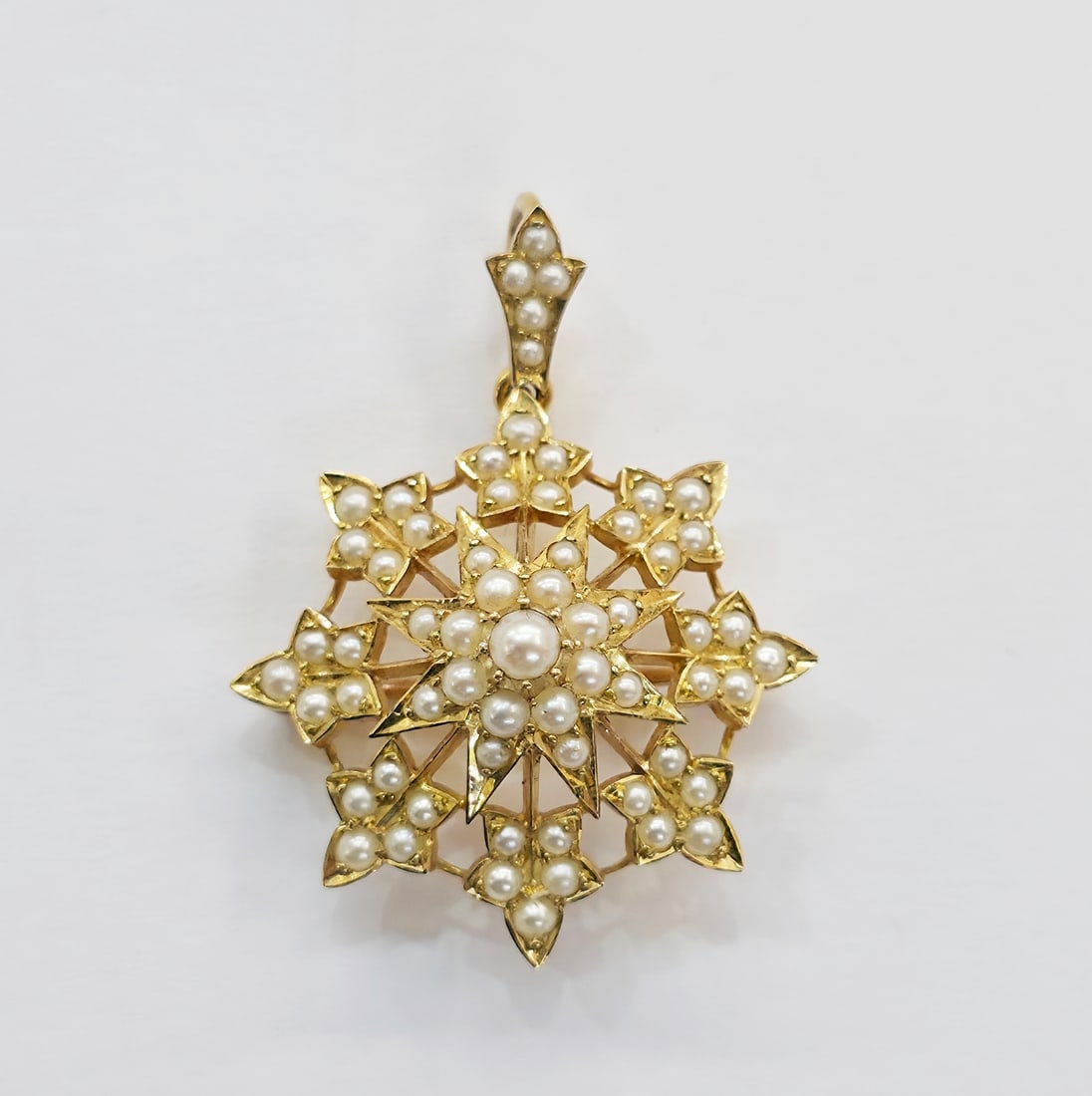 VICTORIAN PEARL STAR BROOCH/PENDANT: VICTORIAN PEARL STAR BROOCH/PENDANT,6 grams, testing high carat gold.Pearls generally well matched.Removable bail.L. 3.6 cm.Fitted case.