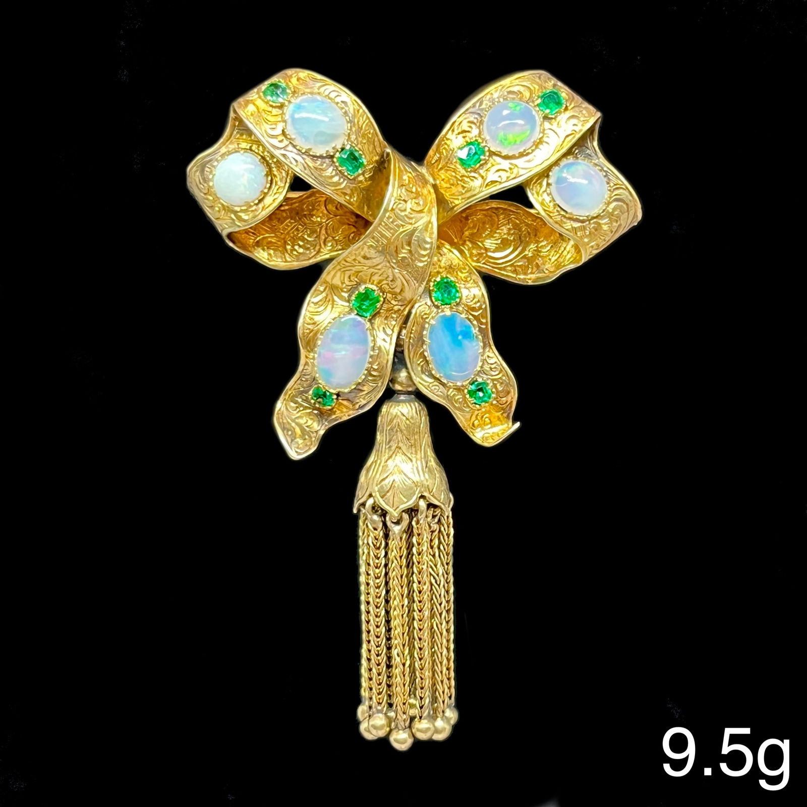 ATTRACTIVE VICTORIAN OPAL AND EMERALD TASSEL BOW BROOCH: ATTRACTIVE VICTORIAN OPAL AND EMERALD TASSEL BOW BROOCH,9.5 grams, testing high carat gold.Rich and vibrant emeralds.Brooch with lovely engraved decoration.Articulated tassel drop.L. 5.6 cm.