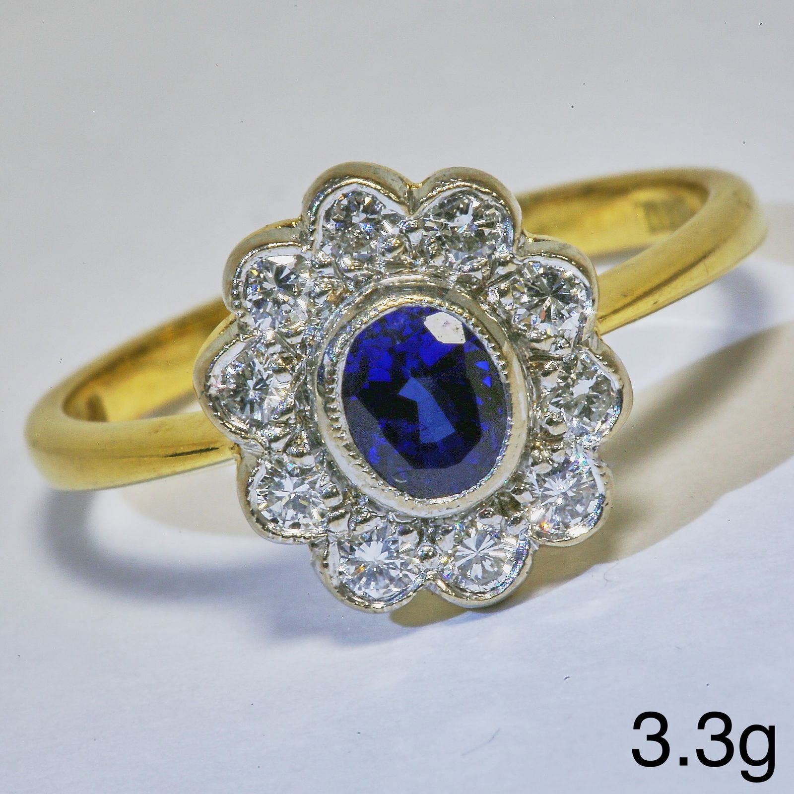 SAPPHIRE AND DIAMOND CLUSTER RING: SAPPHIRE AND DIAMOND CLUSTER RING3.3 grams, marked 18 carat gold. Vibrant sapphire, bright and lively diamonds. Size N.