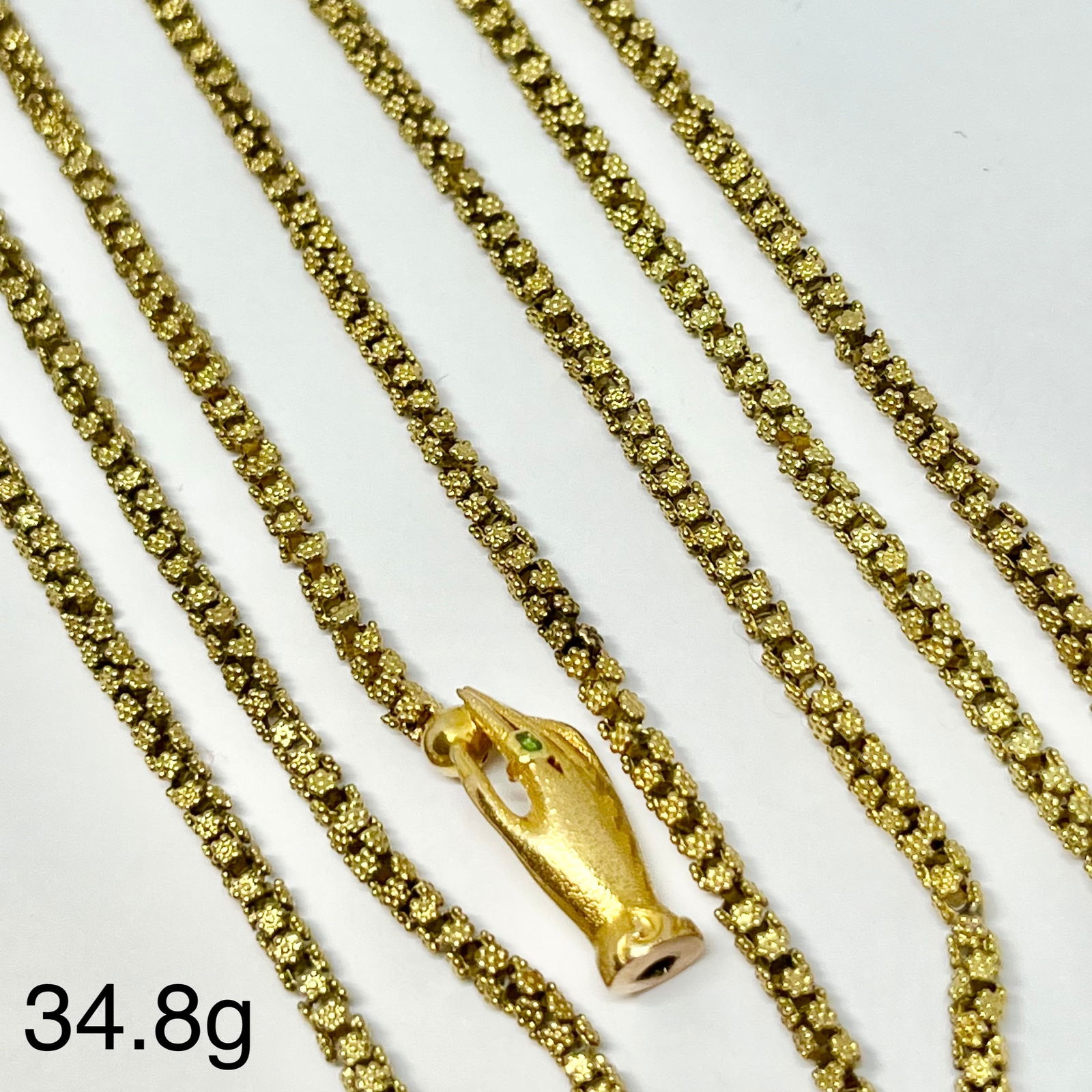 FINE ANTIQUE TRICHINOPOLY CHAIN NECKLACE WITH HAND CLASP: FINE ANTIQUE TRICHINOPOLY CHAIN NECKLACE WITH HAND CLASP,34.8 grams, testing high carat gold.Fine intricate 'trichinopoly' link.The hand clasp set with an emerald.L. 107 cm.