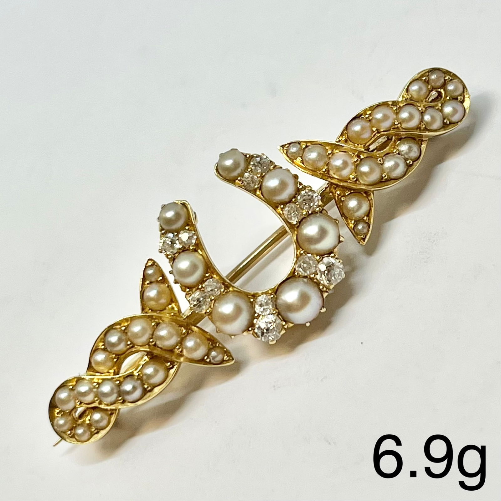 VICTORIAN PEARL AND DIAMOND HORSE SHOE BROOCH: VICTORIAN PEARL AND DIAMOND HORSE SHOE BROOCH,6,9 grams, testing high carat gold.Diamonds bright and lively,Pearls generally well matched.W. 4.6 cm.
