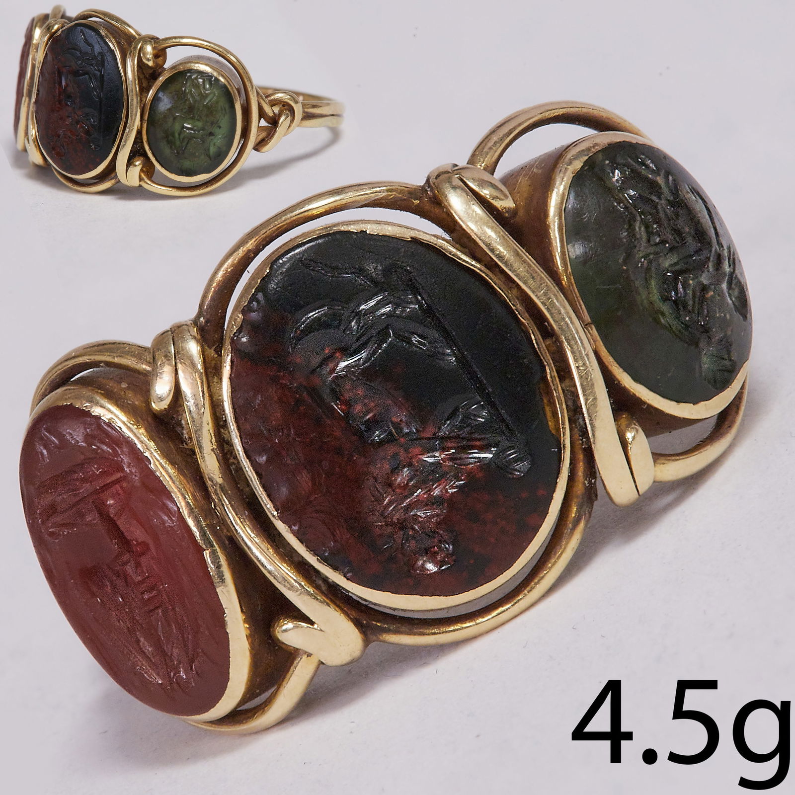 ANTIQUE 3-STONE INTAGLIO RING, possibly ancient: ANTIQUE 3-STONE INTAGLIO RING, possibly ancient.4.5 grams, high carat gold.The centre red and green jasper intaglio depicting a lion.The sides depicting a mother with child and a beetle.Intaglio's