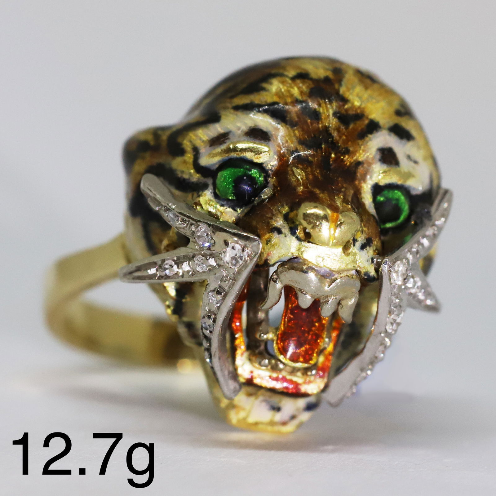 UNUSUAL DIAMOND AND ENAMEL TIGERS HEAD RING: UNUSUAL DIAMOND AND ENAMEL TIGERS HEAD RING,12,7 grams, testing 18 ct. gold.Fine multi-colour enamel.Diamonds bright and lively.Size O.