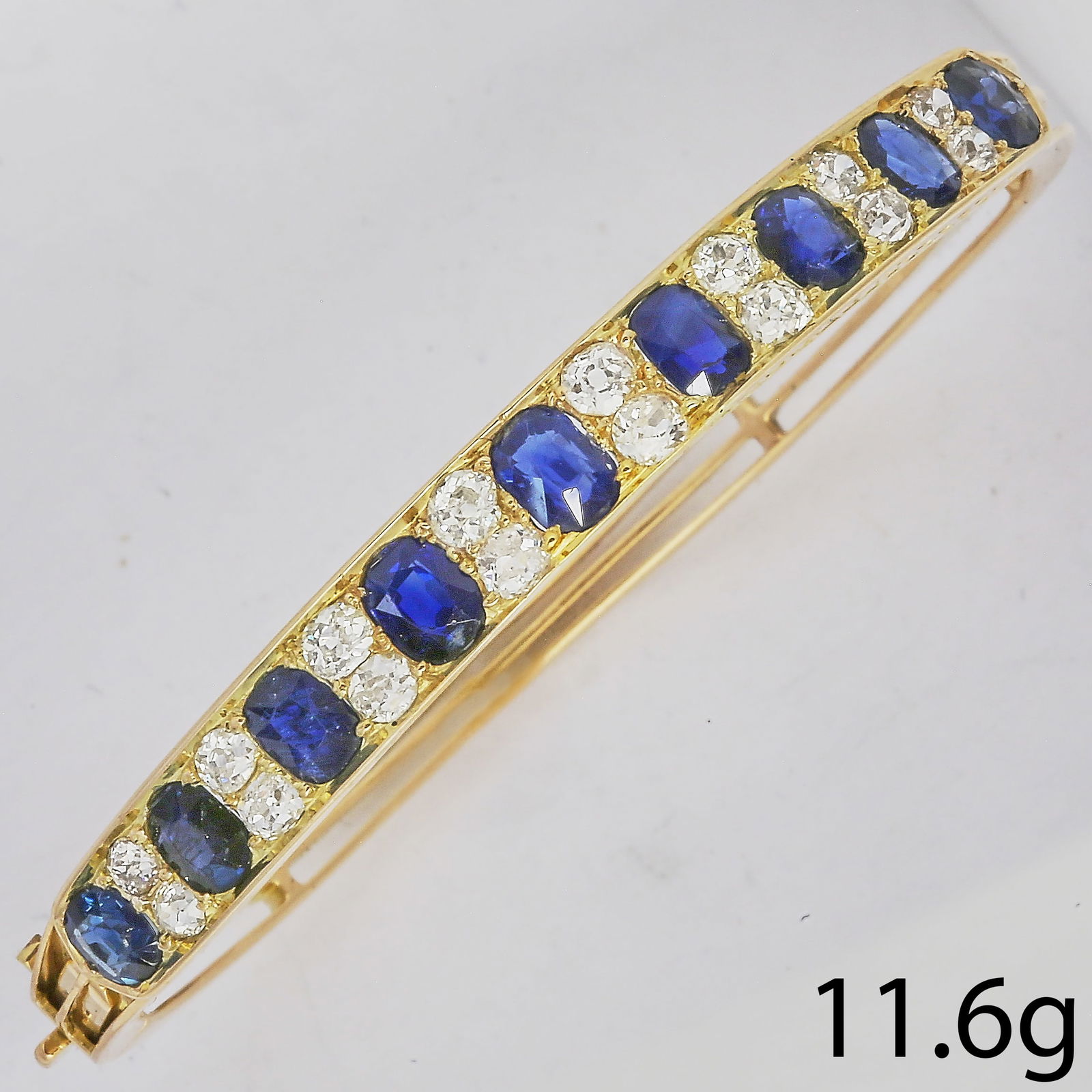 FINE SAPPHIRE AND DIAMOND HINGED BANGLE: FINE SAPPHIRE AND DIAMOND HINGED BANGLE,11,6 grams, testing high carat gold.Rich and vibrant sapphires, totalling approx. 6 ct.Diamonds bright and lively totalling approx. 1.60 ct.Inner diam. 5.3 cm.