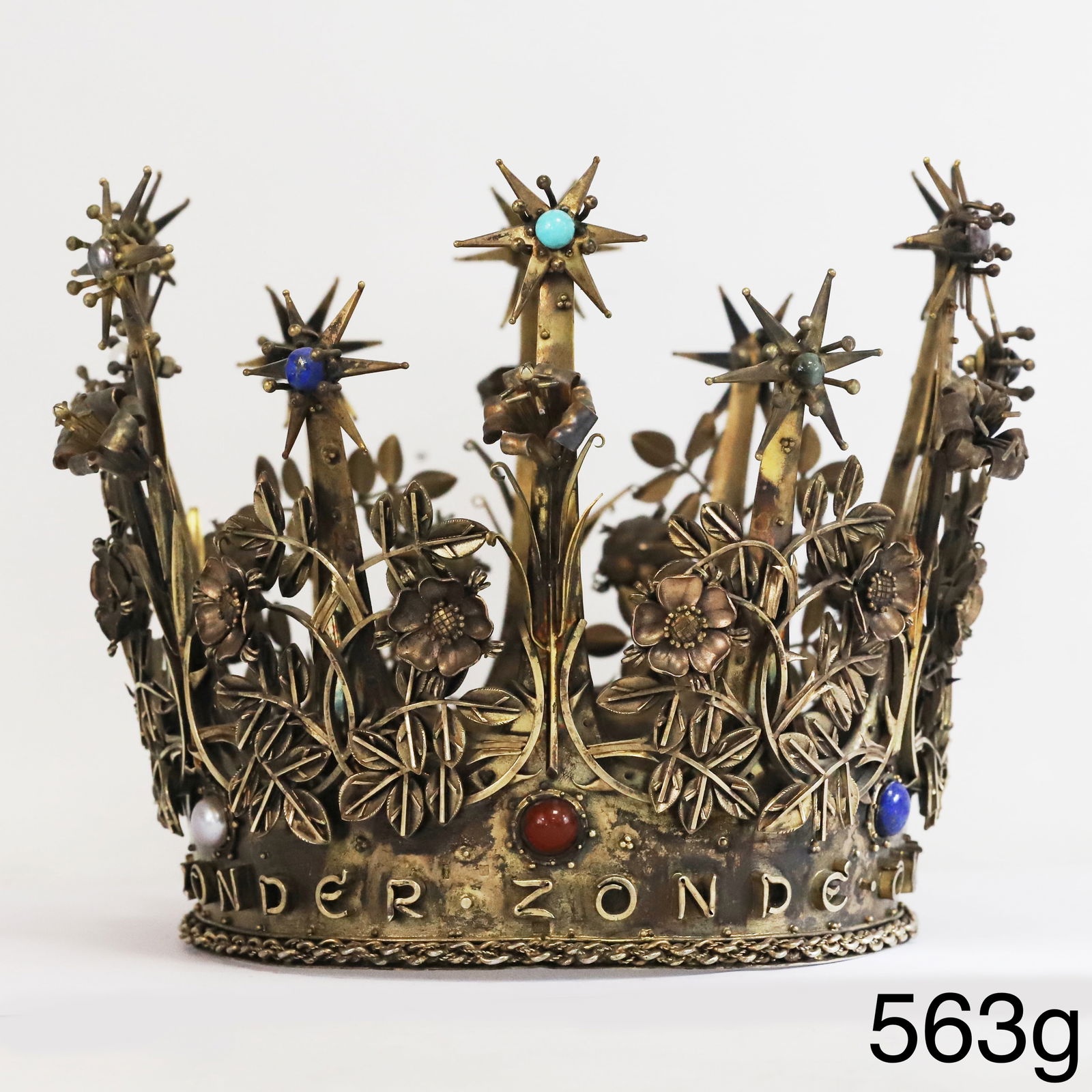 FINE AND RARE GEMSET CROWN: FINE AND RARE GEMSET CROWN,563 grams.The crown of rich relief floral design.Accentuated with gemstones including lapis lazuli and tigers eye.Surrounder with text: Maria zonder zonde ontvagen.H. 15