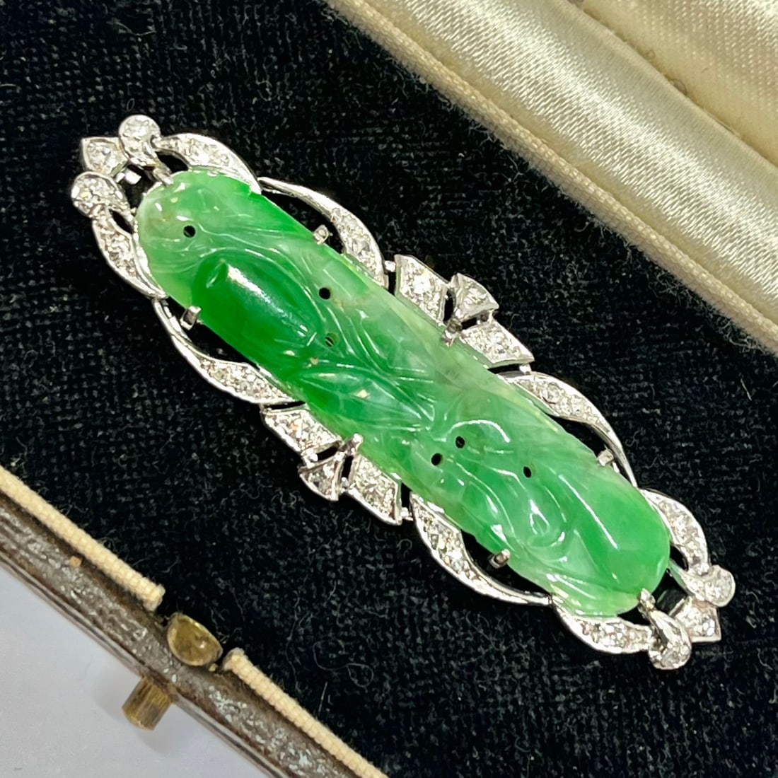 ART-DECO JADE AND DIAMOND BROOCH: ART-DECO JADE AND DIAMOND BROOCH,8,6 grams, testing platinum.Diamonds bright and lively.Lovely carved green jade plaque.W. 5.3 cm.Fitted Liberty case.