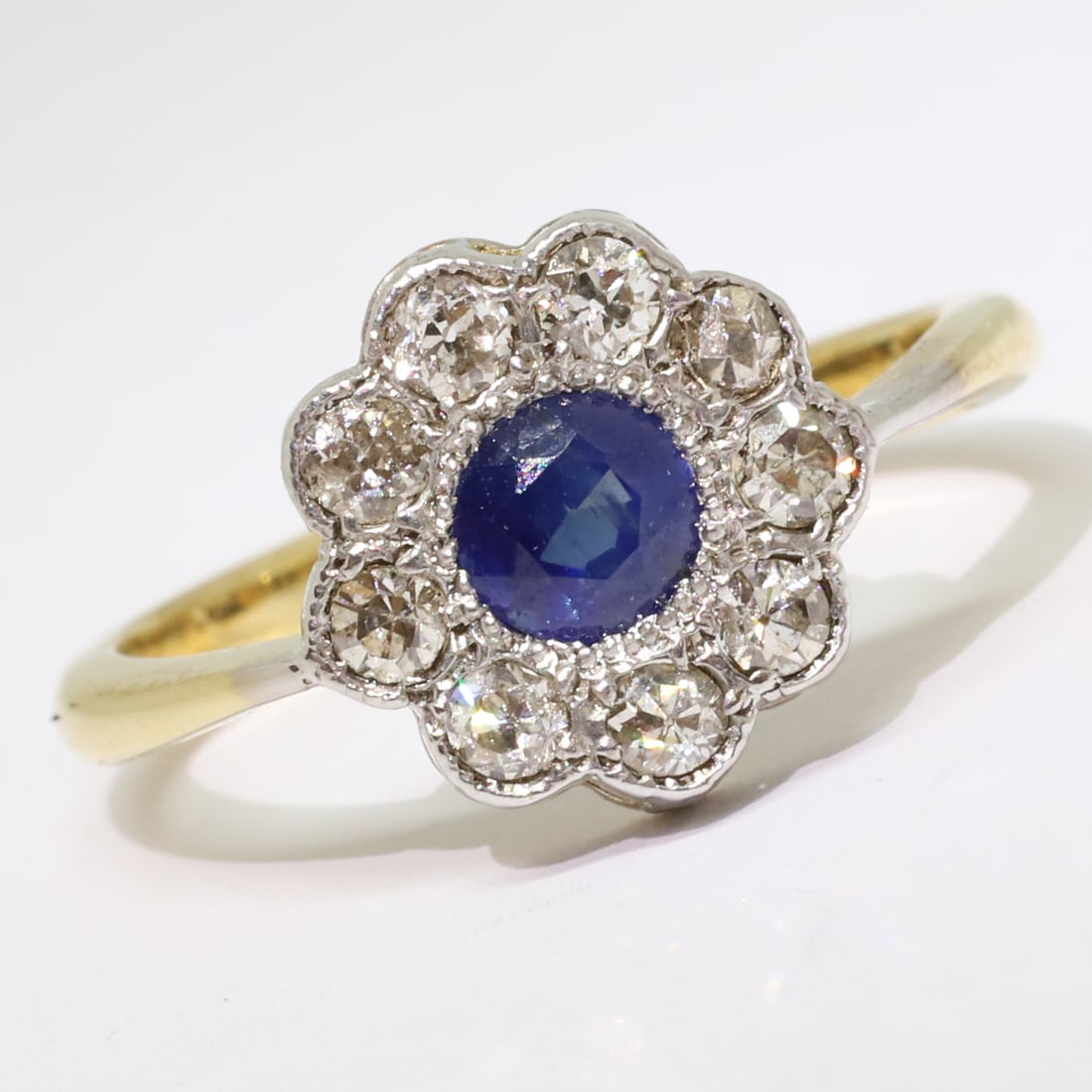 EDWARDIAN SAPPHIRE AND DIAMOND CLUSTER RING: EDWARDIAN SAPPHIRE AND DIAMOND CLUSTER RING,3,6 grams, testing high carat gold.Vibrant sapphire of approx. 0.60 ct.Diamonds bright and lively.Size N.