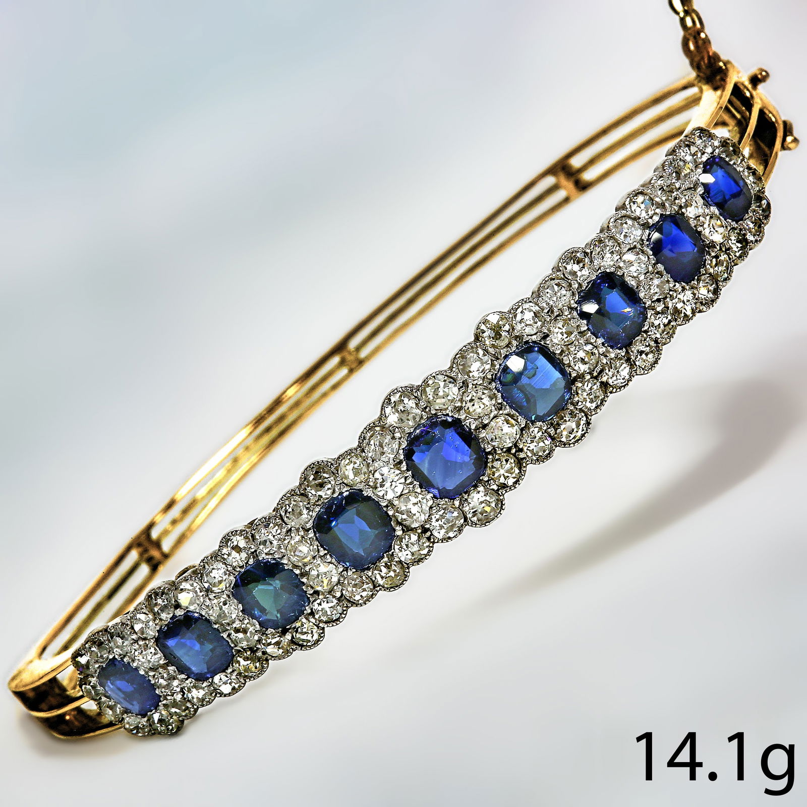 SAPPHIRE AND DIAMOND BANGLE: SAPPHIRE AND DIAMOND BANGLE,14.1 grams. testing high carat gold. Vibrant sapphires, totalling approx. 4.50 ct.Diamonds bright and lively, totalling approx. 3.70 ct.Inner diam. 6 cm.