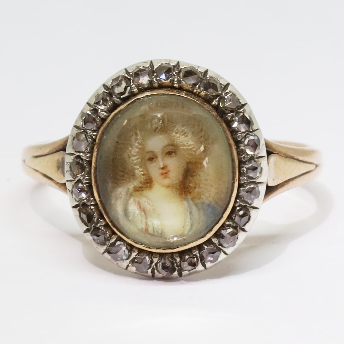 UNUSUAL ANTIQUE DIAMOND PORTRAIT RING: UNUSUAL ANTIQUE DIAMOND PORTRAIT RING,3 grams, 18 ct. gold (French marked).Set with lovely painted miniature of an elegant lady.Surrounded with diamonds.Size M.