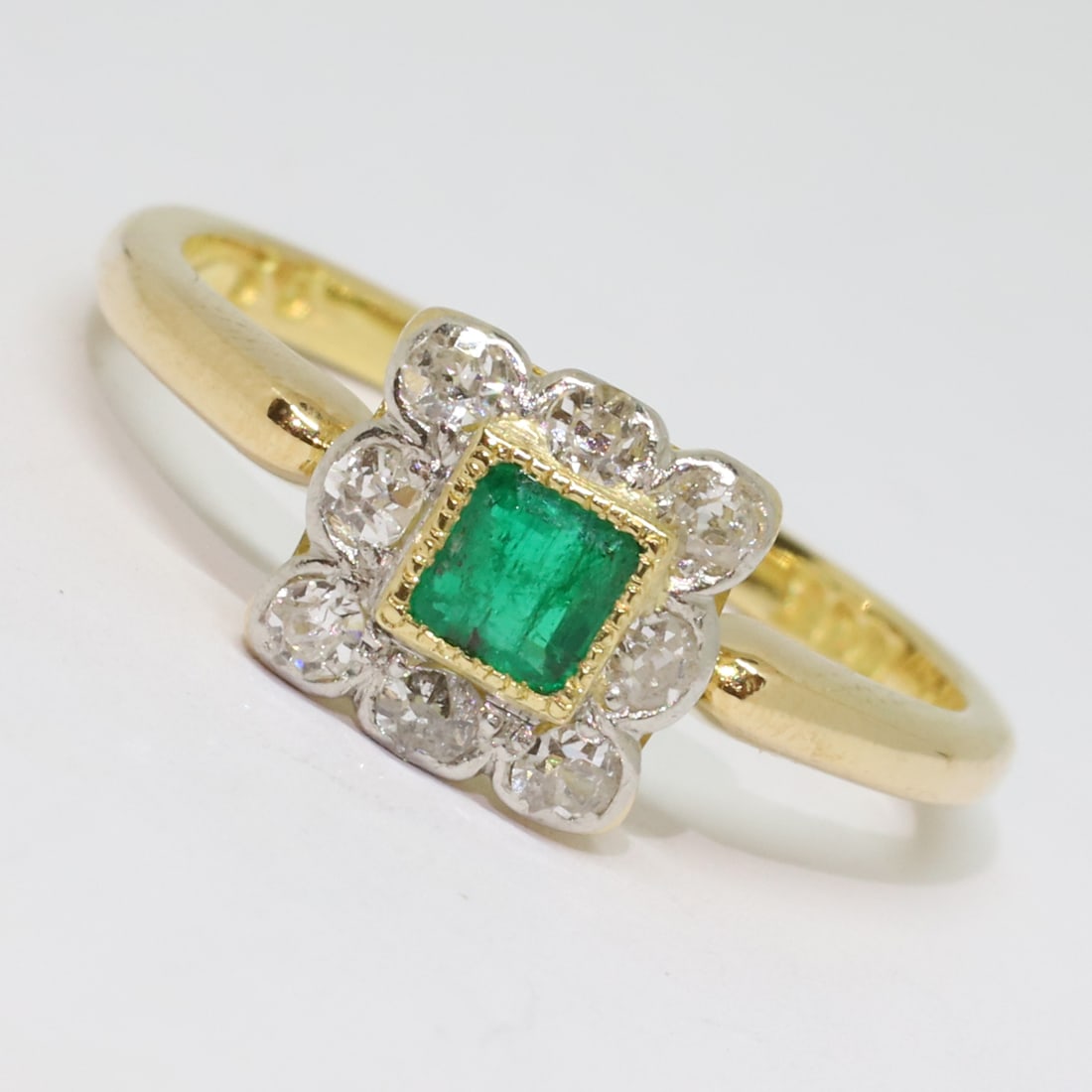 EMERALD AND DIAMOND CLUSTER RING: EMERALD AND DIAMOND CLUSTER RING,18 ct. gold and platinum.Rich and vibrant emerald.Diamonds bright and lively.Size M.