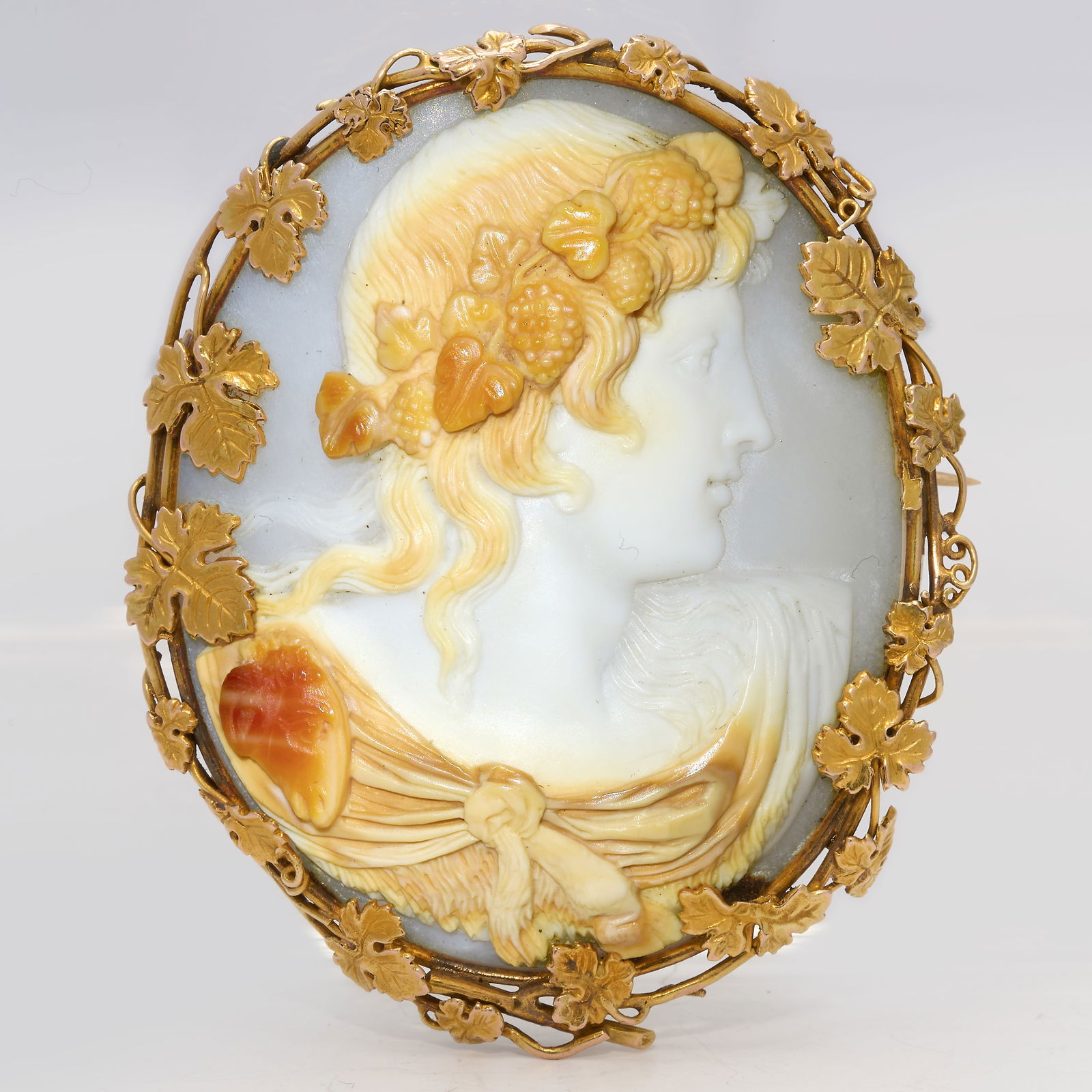 VICTORIAN CAMEO BROOCH: VICTORIAN CAMEO BROOCH,20.1 grams. Testing high carat gold.The fine carved cameo depicting a bacchante.The surmount with fine gold work with relief vine leaves.L. 5.5 cm.