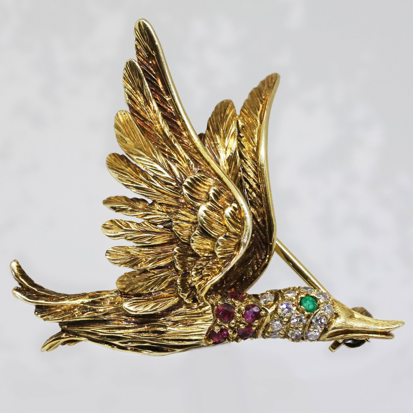 VICTOR MEYER, EMERALD RUBY AND DIAMOND DUCK BROOCH: VICTOR MEYER, EMERALD RUBY AND DIAMOND DUCK BROOCH,7.1 grams, testing high carat gold.Duck in flight.Vibrant emerald and rubies.Diamonds bright and lively,.Makers mark VM for Victor Meyer.W. 3.6 cm.