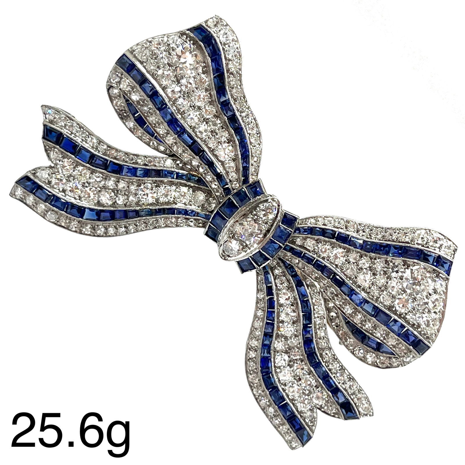 EXCEPTIONAL ART-DECO SAPPHIRE AND DIAMOND BOW BROOCH: EXCEPTIONAL ART-DECO SAPPHIRE AND DIAMOND BOW BROOCH,25.6 grams, testing platinum.Bright and lively diamonds, totalling approx. 8.60 ct.Rich and vibrant sapphires, totalling approx. 6 ct.W. 7.4 cm.Wit